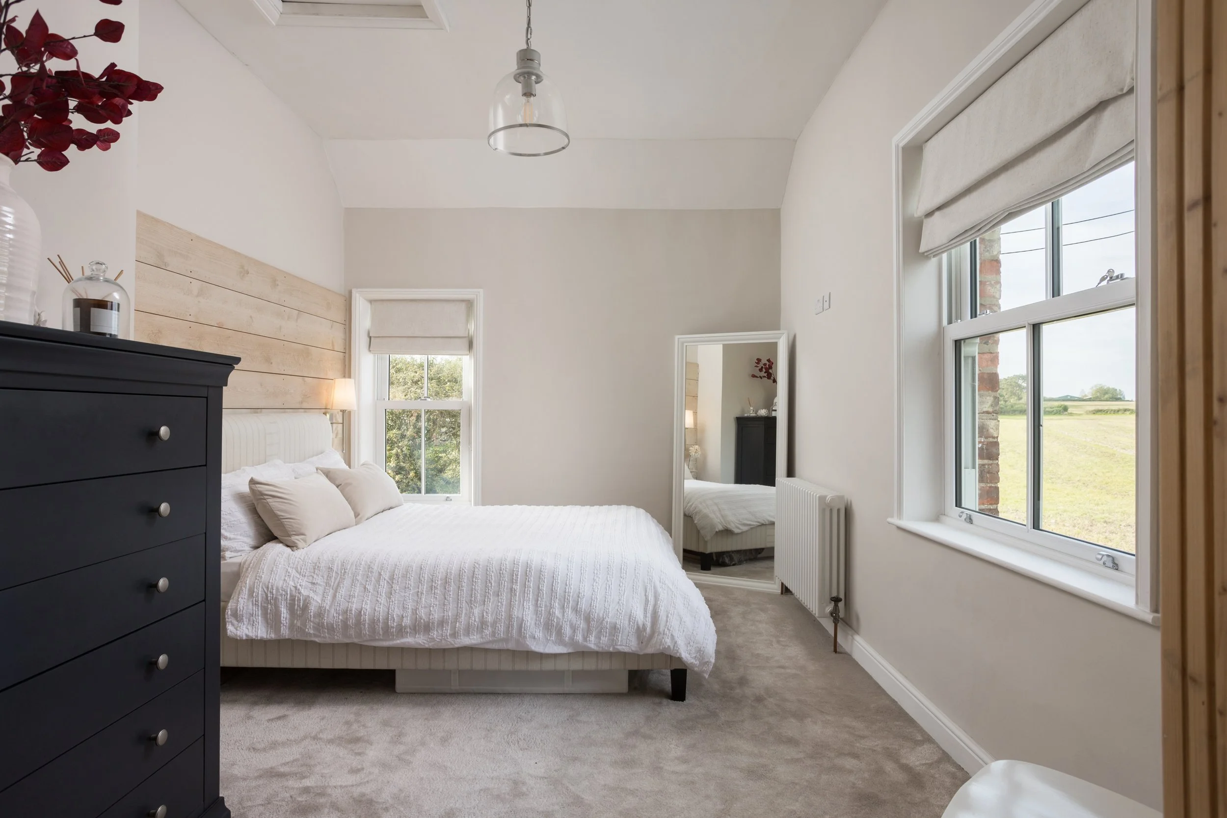 a bedroom with timber of the bed head wall, and views of out the window to the countryside