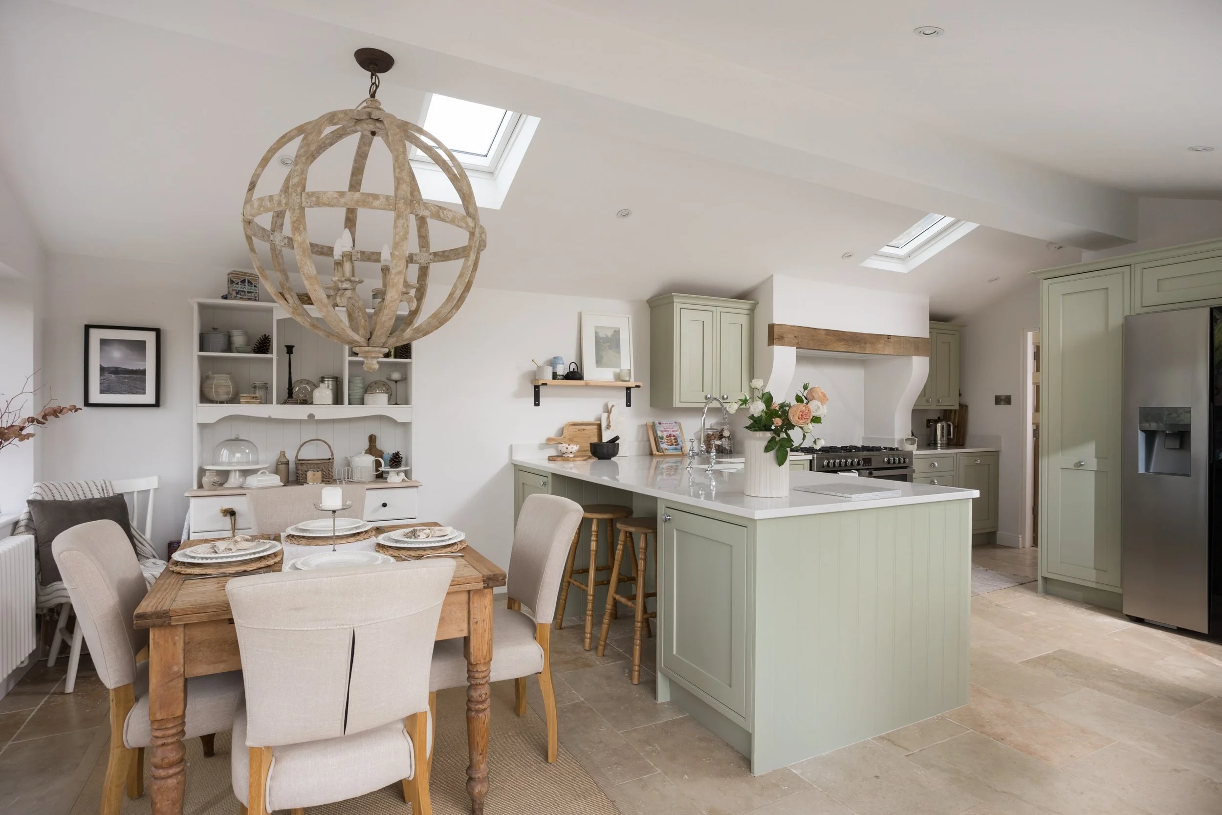 open plan lofted ceiling kitchen/dining room with skylights, tile flooring and pale green worktops