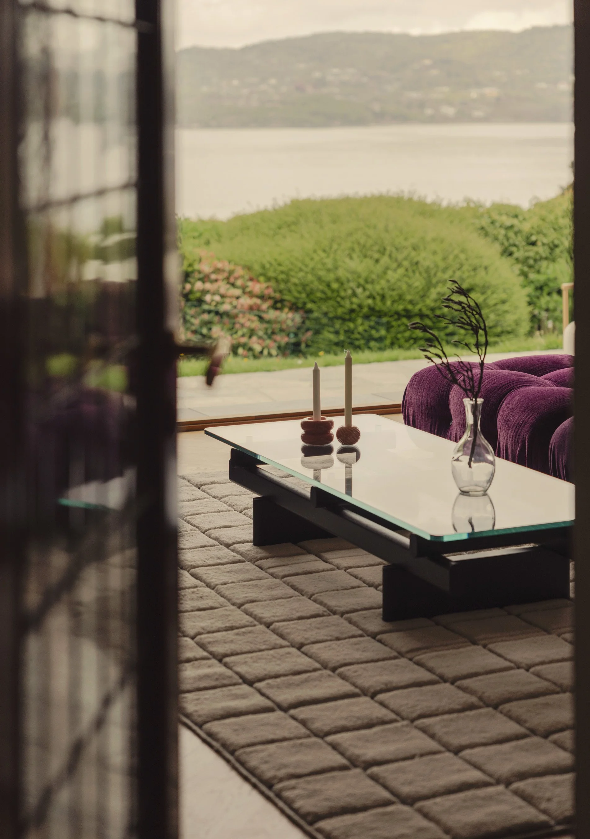 Stue med rosa sofa mot åpen glassdør og grønne busker