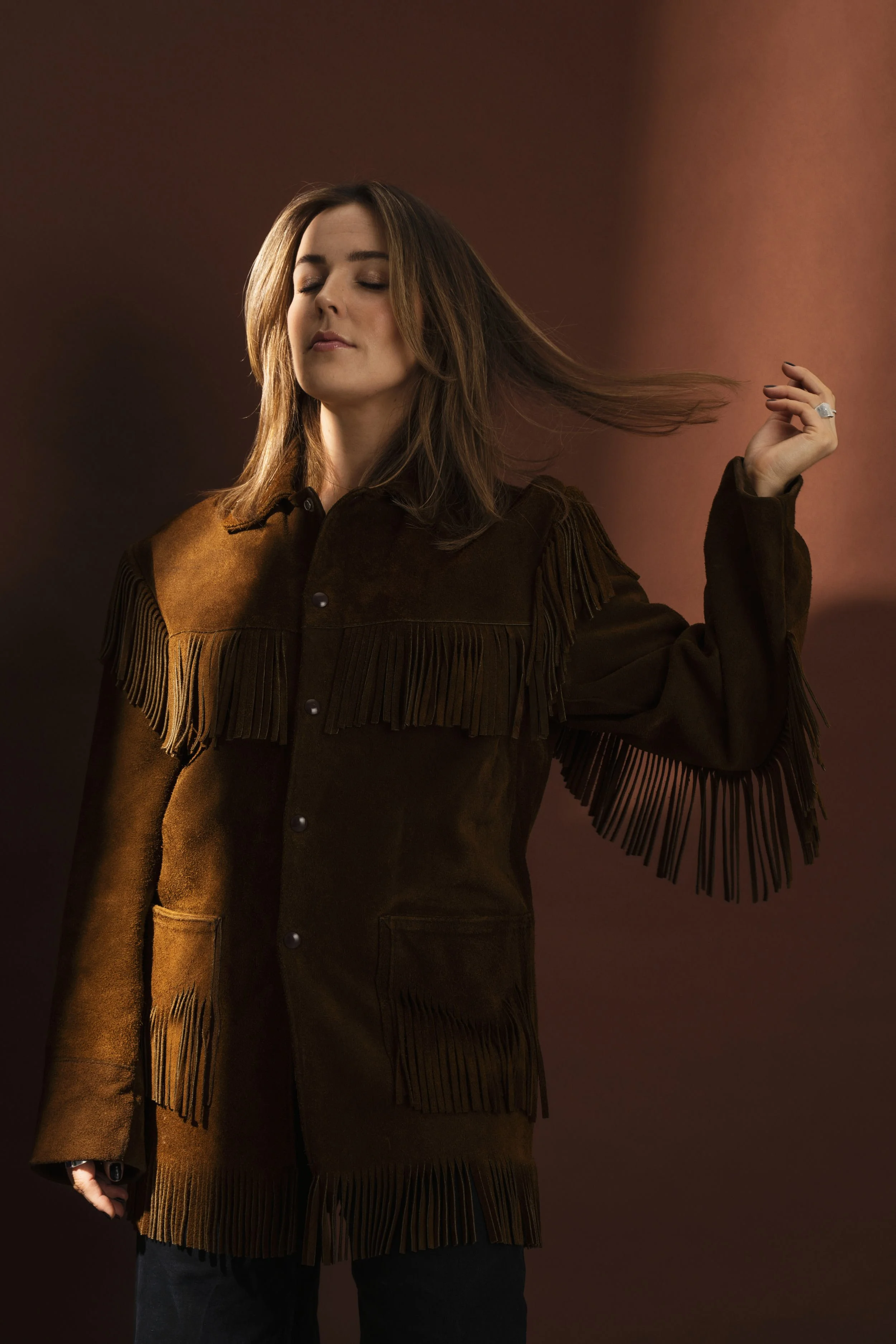 Dame med brunt tøy mot brun bakgrunn.