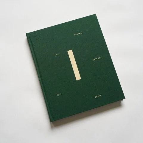 Green book titled 'Portrait of a Cricket' by Tom Shaw on a white surface