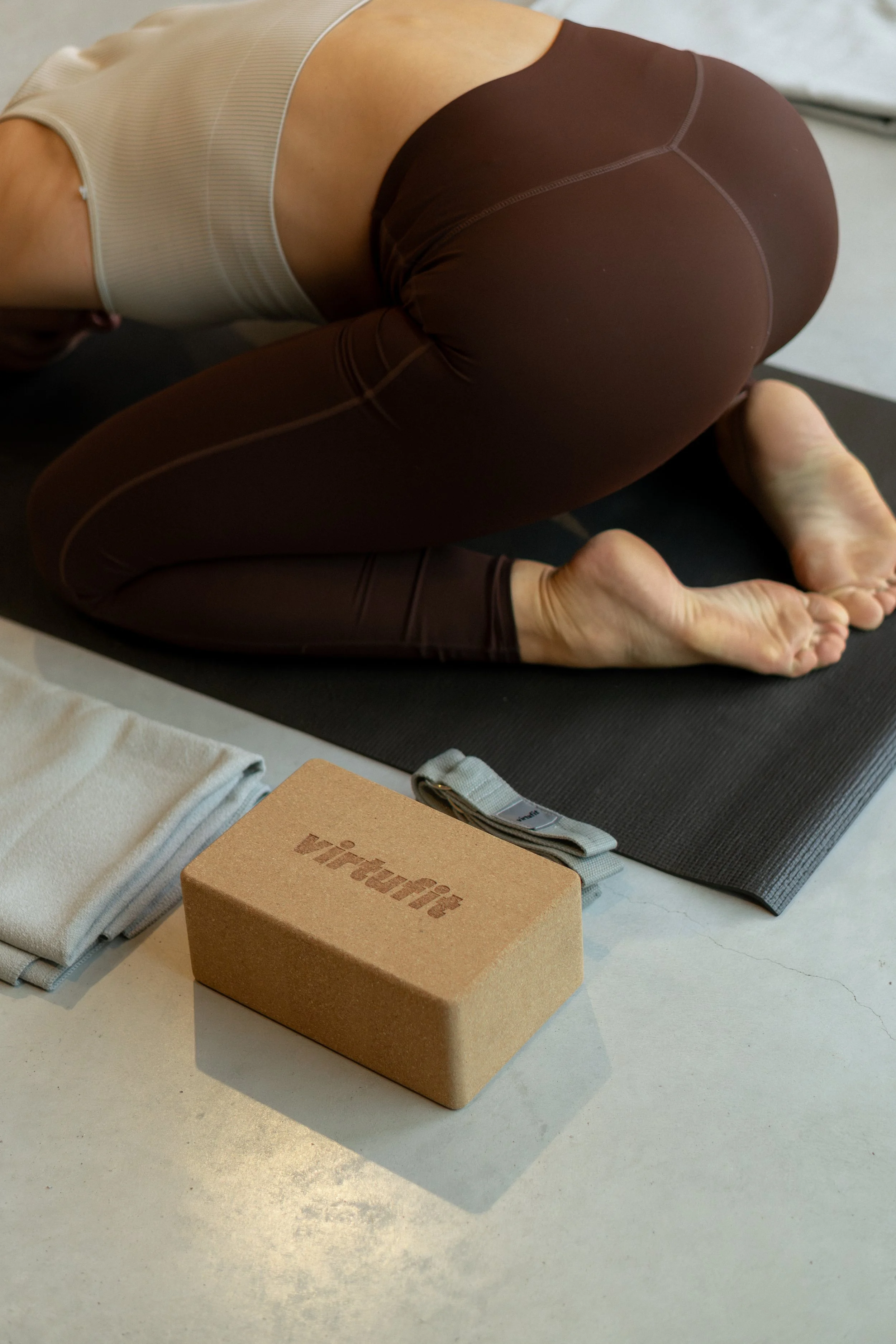 Persoon die yoga doet op een mat, met blokken, handdoek en riem in een binnenruimte.