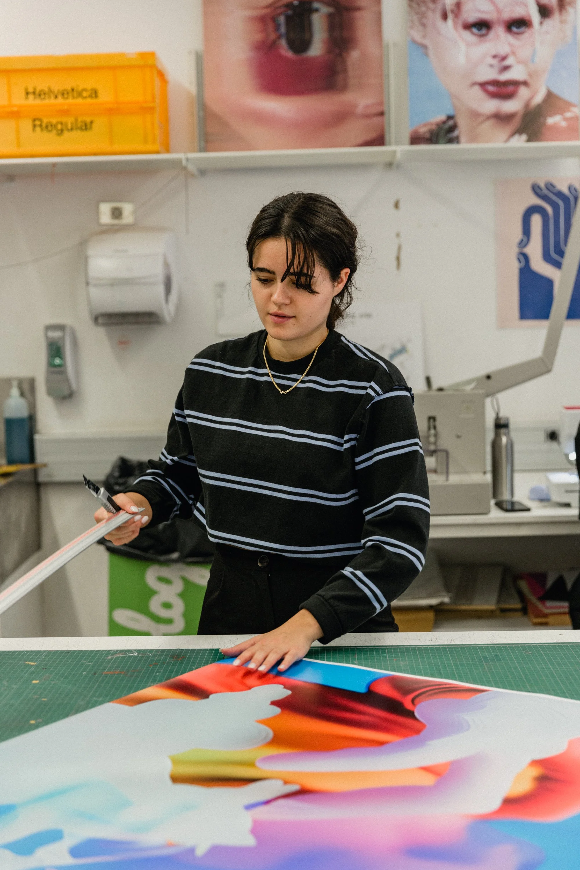 A woman working on a colorful art project at a table in an art studio.