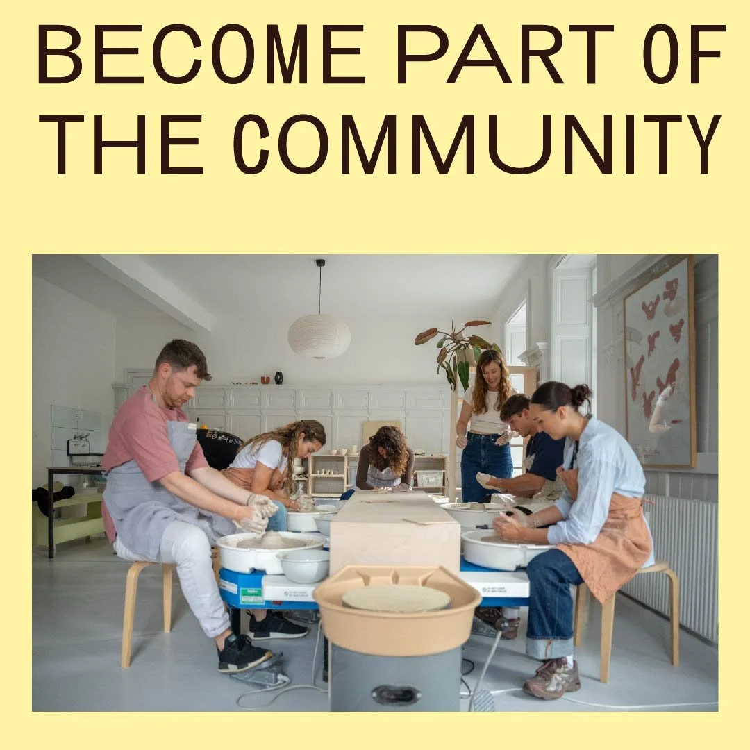Group of people participating in a pottery or ceramics class in a bright room, working on pottery wheels.