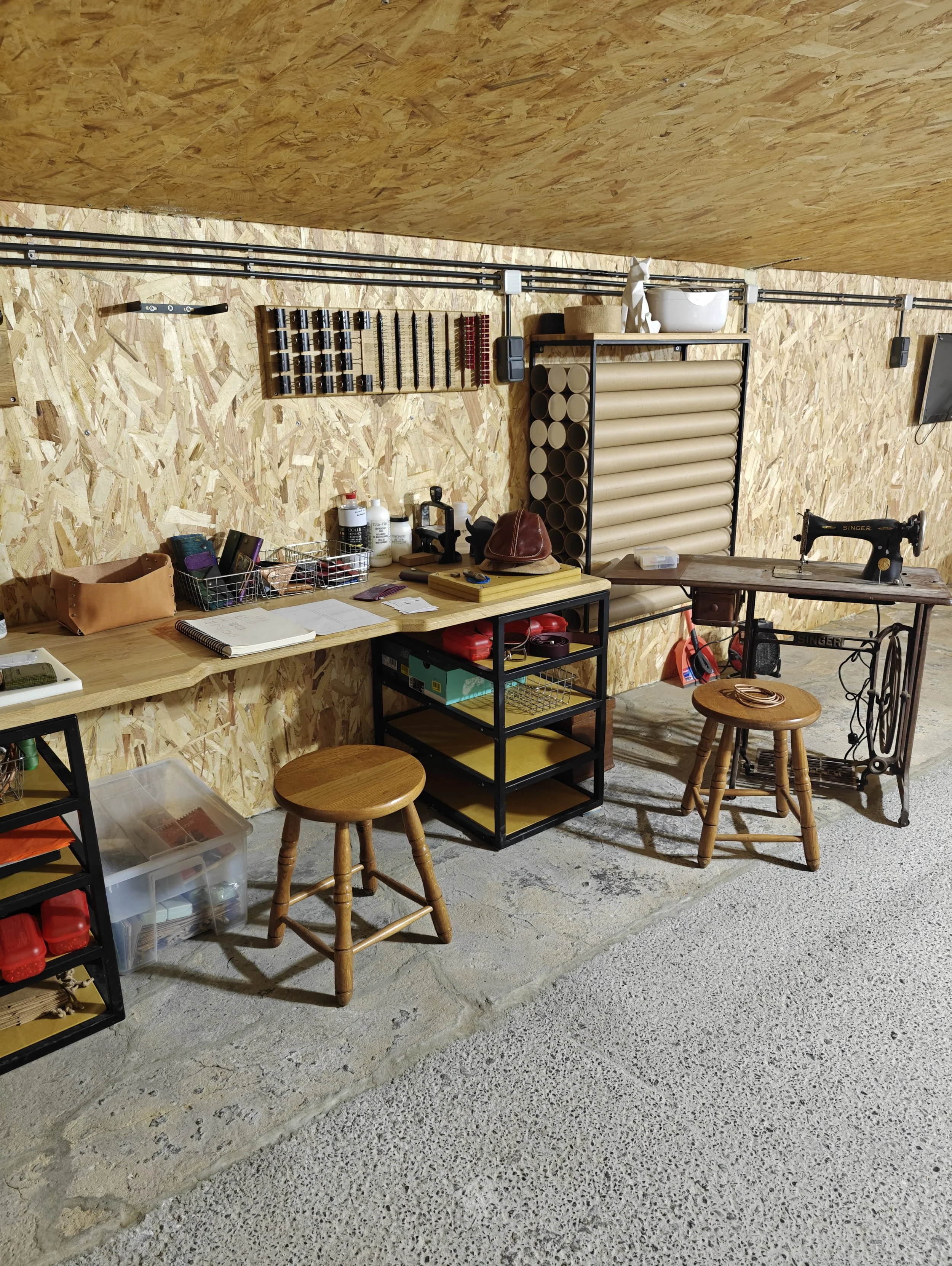 Aménagement temporaire du nouvel atelier. Machine à coudre historique et établi de travail sur mesure.