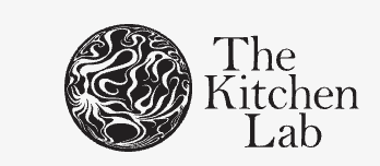 Logo for The Kitchen Lab featuring a black circular design with white abstract swirl patterns, and the text 'The Kitchen Lab' next to it.