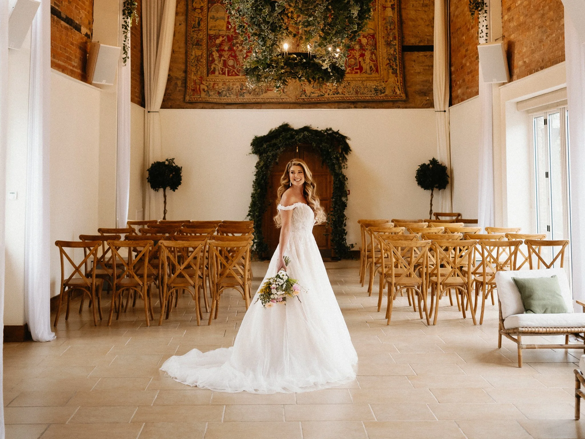 Bride walking through the barn doorway holding her bouquet at The Barns at Delbury Hall, Craven Arms.