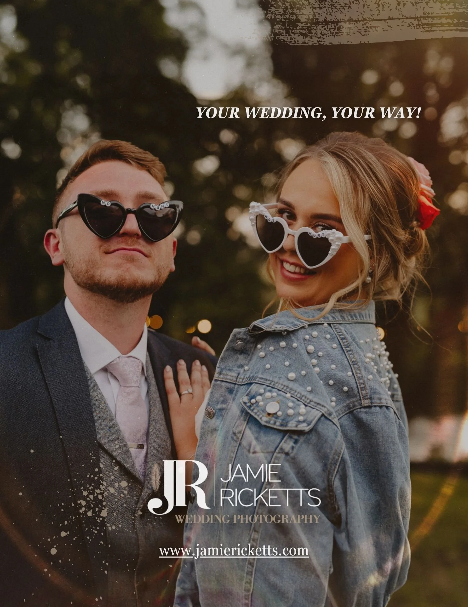 A smiling couple at a wedding, wearing heart-shaped sunglasses, with a blurred outdoor background and wedding photography branding.