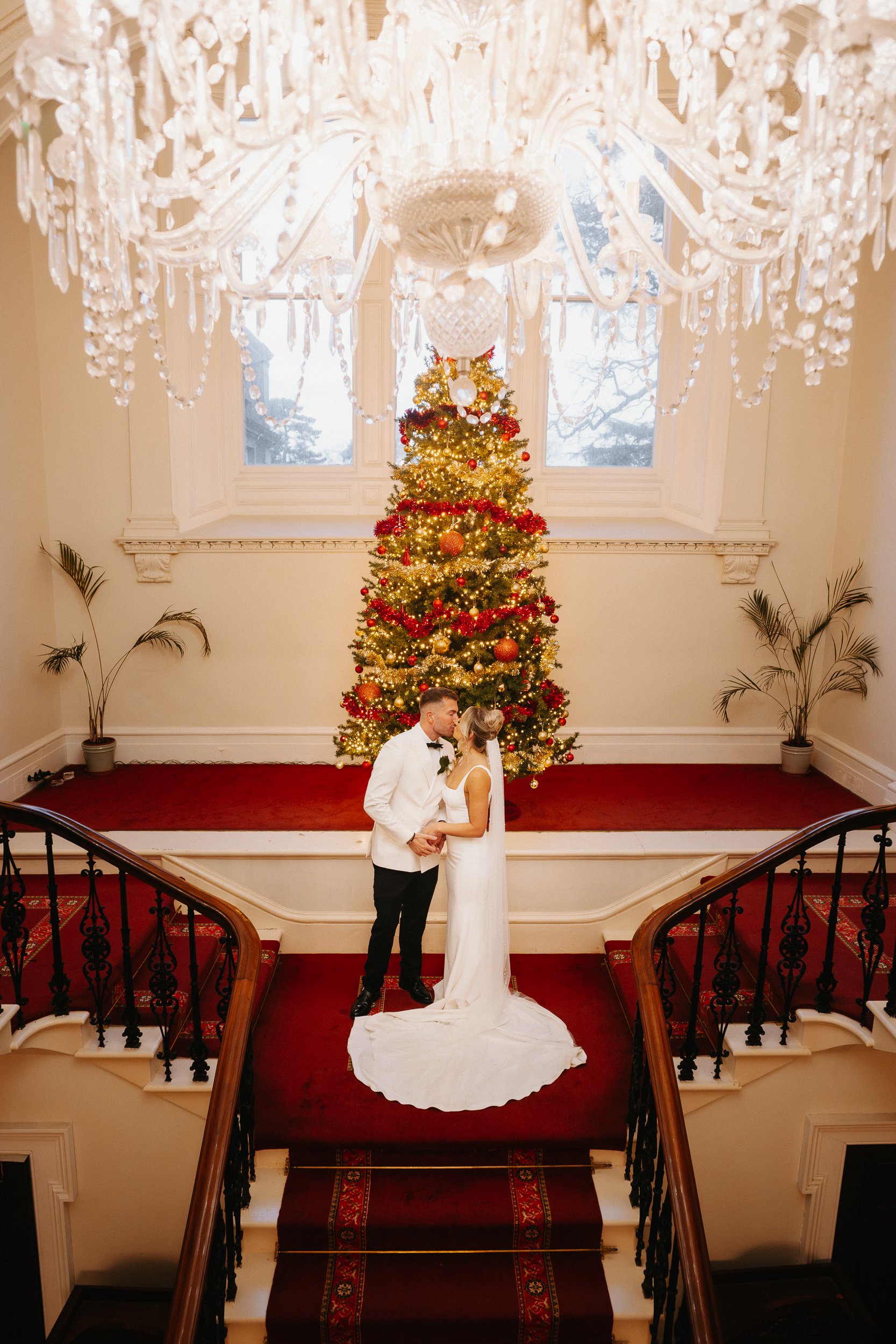 Bride and groom posing for portraits on the grand staircase inside Netley Hall during their winter wedding celebration.