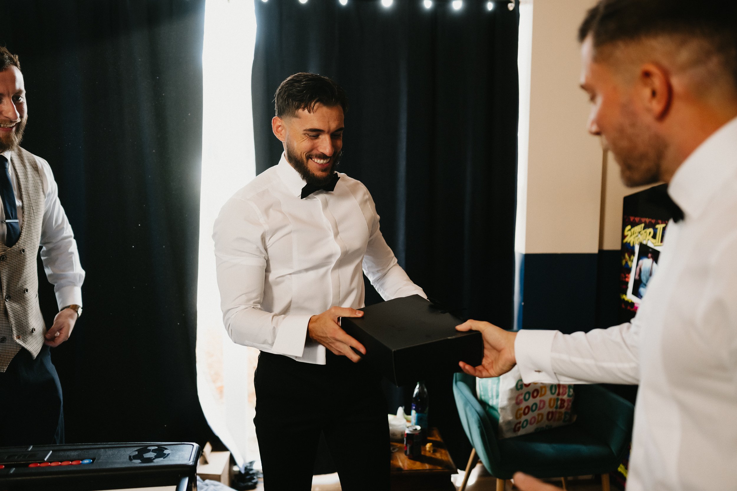 Groom giving gifts to his groomsmen before ceremony at Netley Hall winter wedding