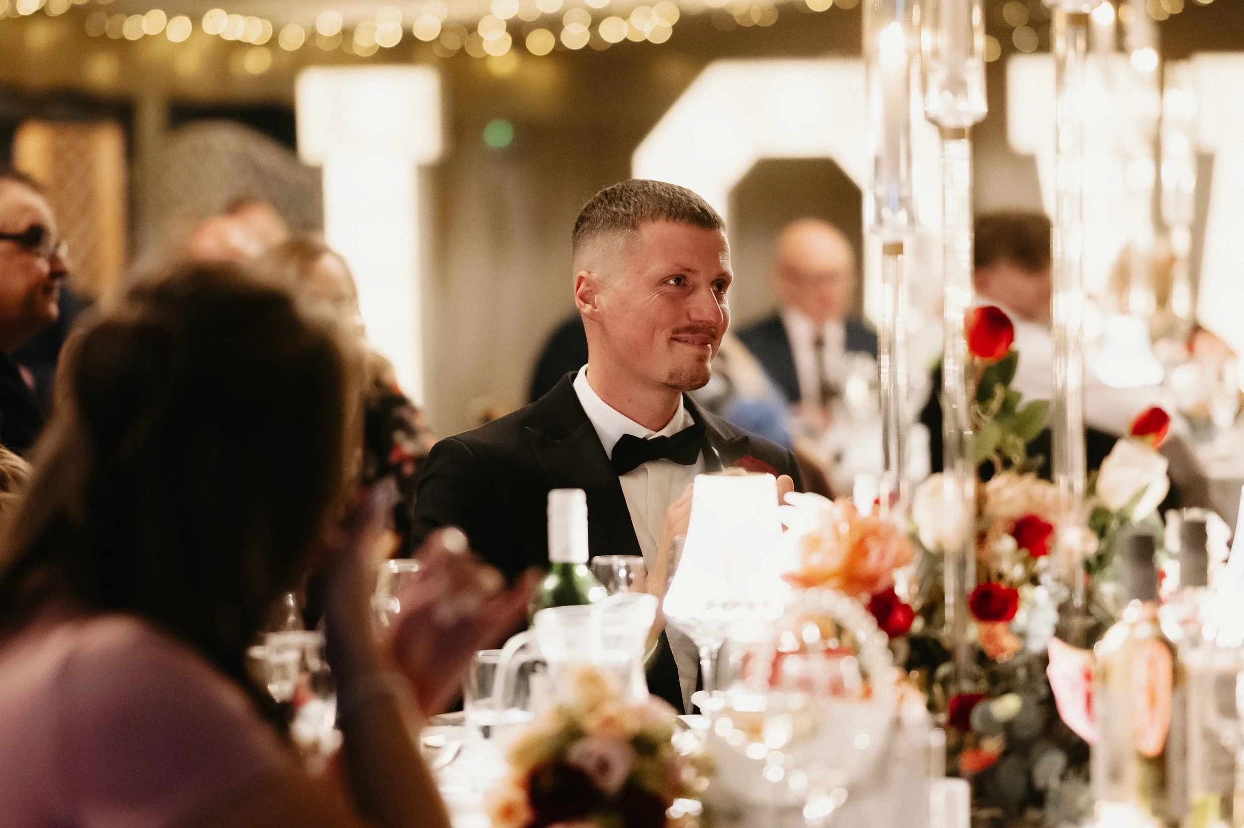 Wedding speeches taking place during the winter wedding breakfast at Netley Hall, with guests listening and reacting around the room.