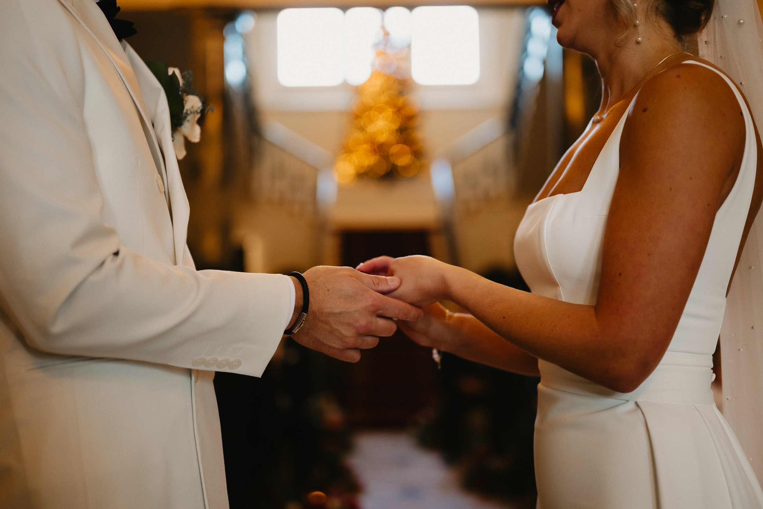Bride and groom during their winter wedding ceremony inside Netley Hall in Shropshire, with guests seated around them.