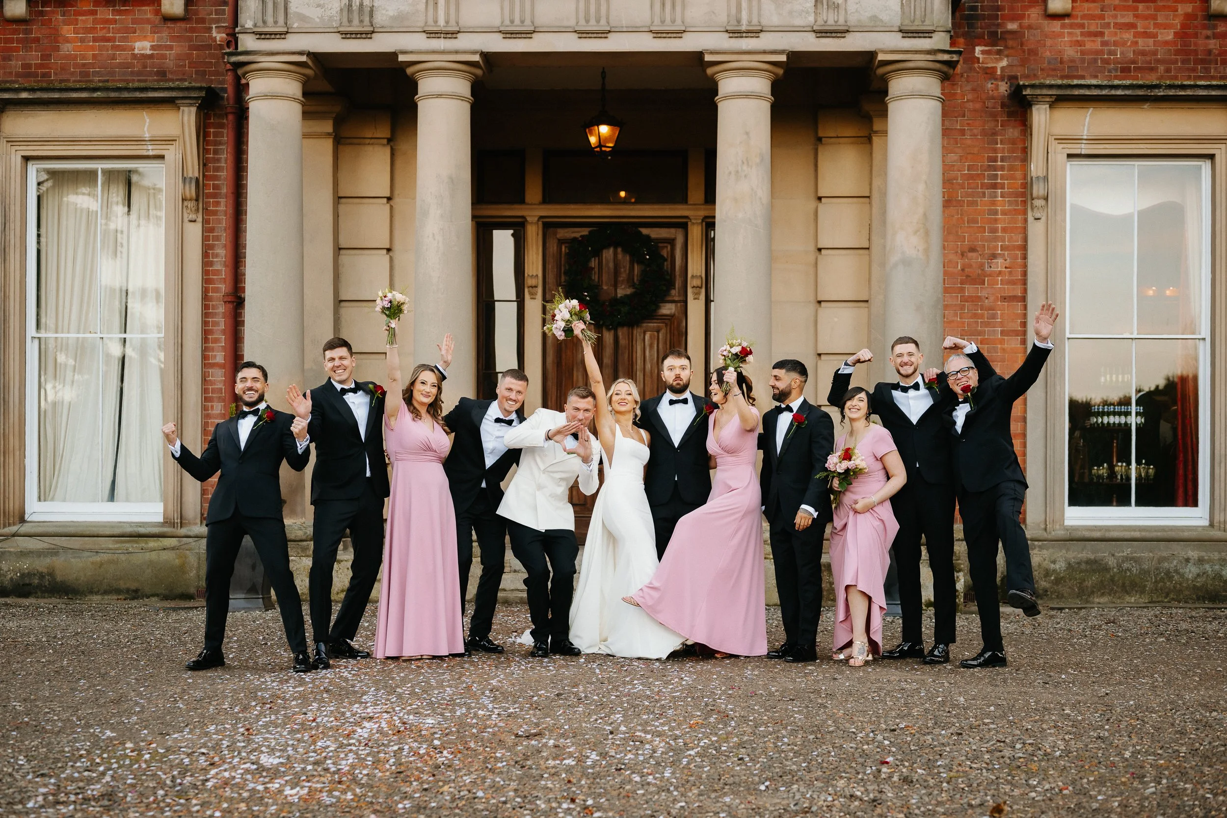 Bride and groom posing with bridesmaids and groomsmen for a group photo outside Netley Hall during their winter wedding celebration.