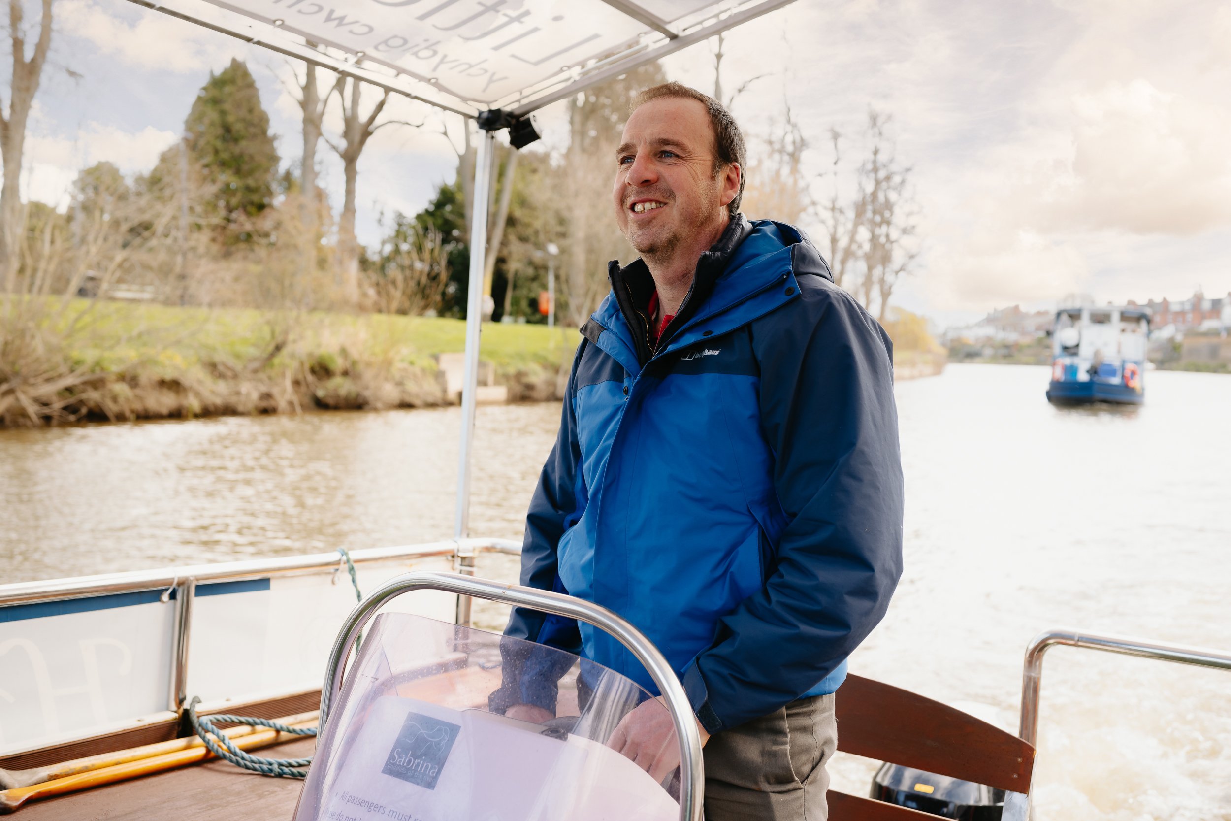 The Sabrina Boat carrying passengers along the River Severn in Shrewsbury, with the open green space of Shrewsbury Quarry visible in the background in Shropshire.