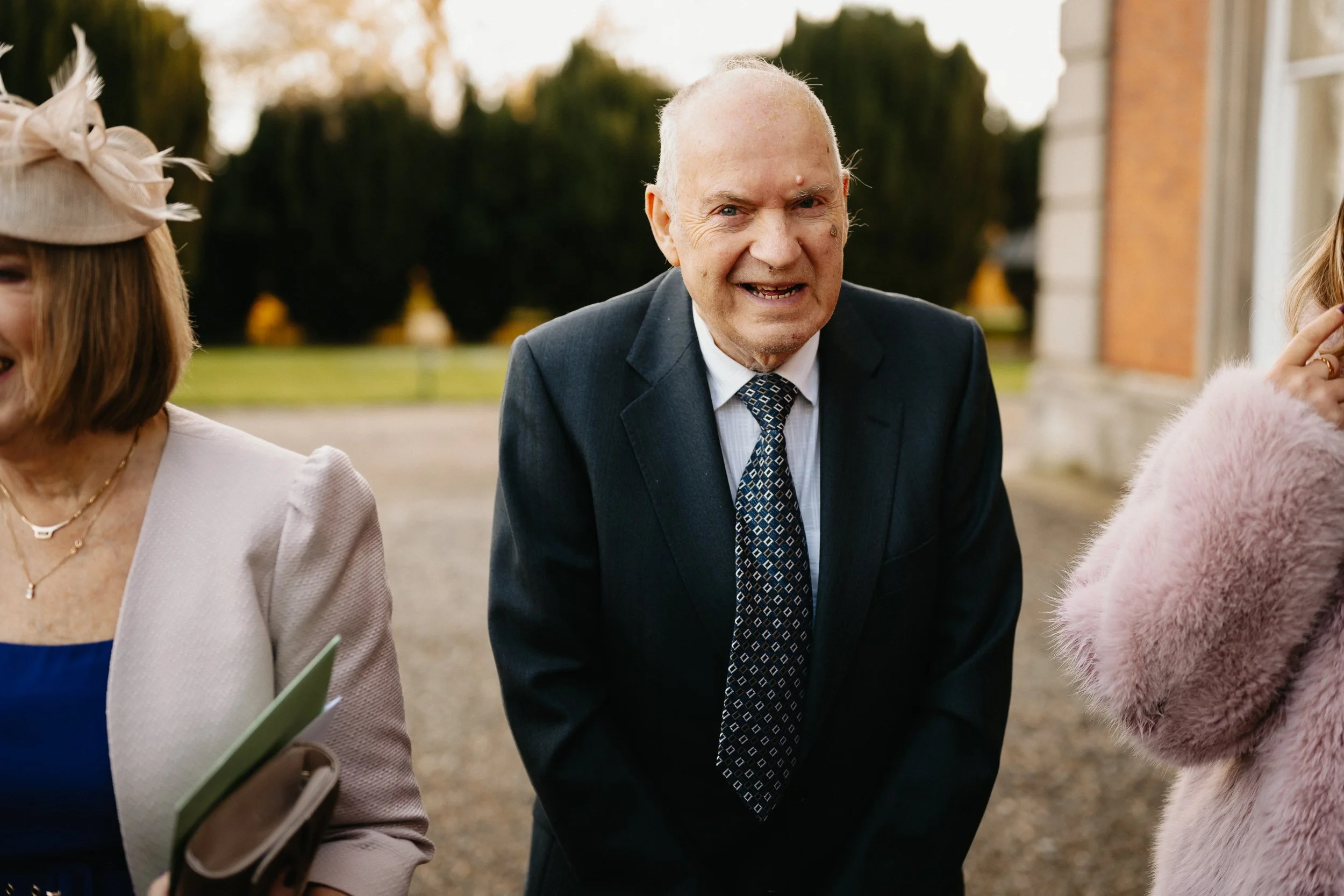 Wedding guests gathering outside Netley Hall during a winter wedding, holding confetti and getting ready to celebrate the newlyweds.