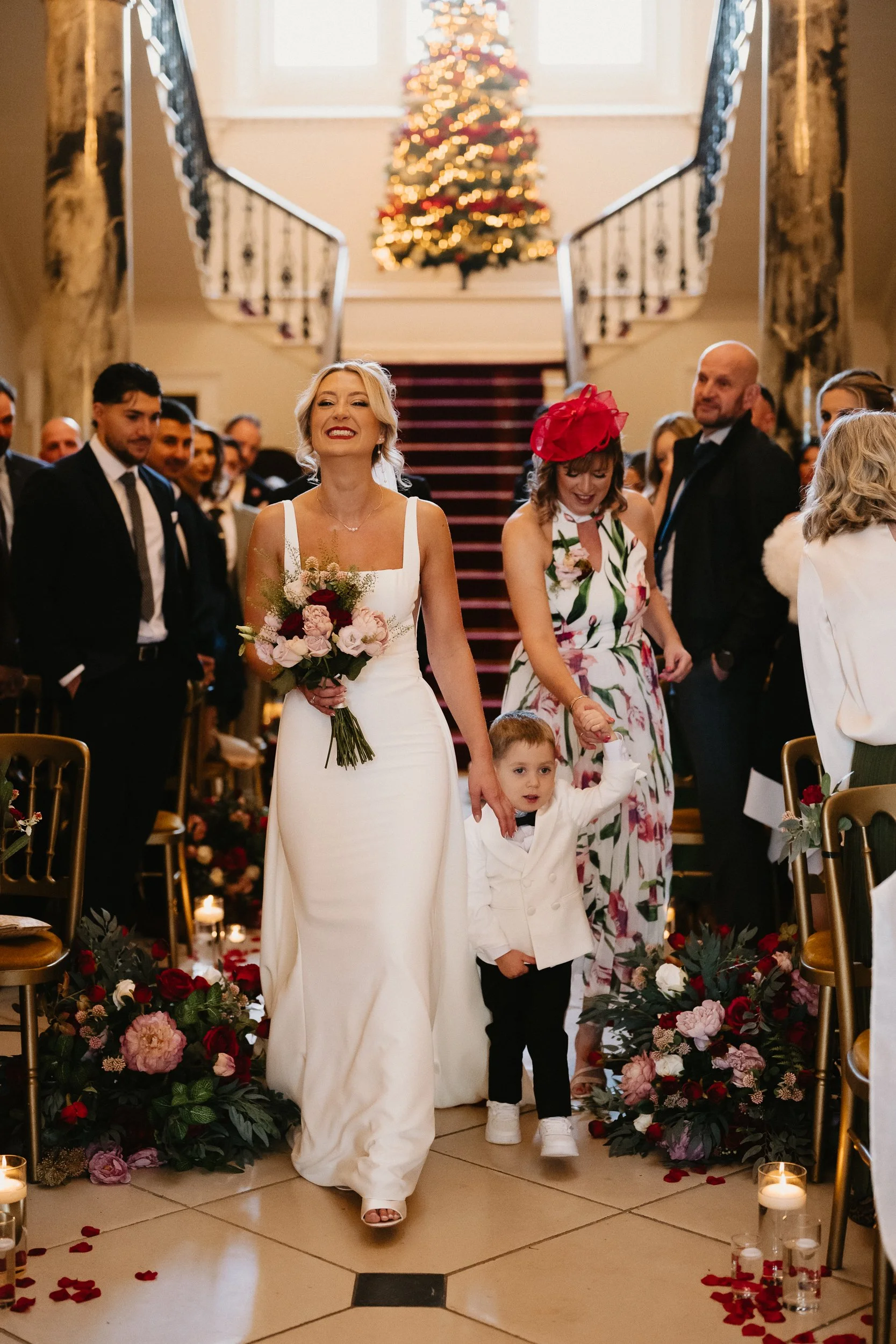 Bride walking down the grand staircase inside Netley Hall during her winter wedding, moments before the ceremony begins.