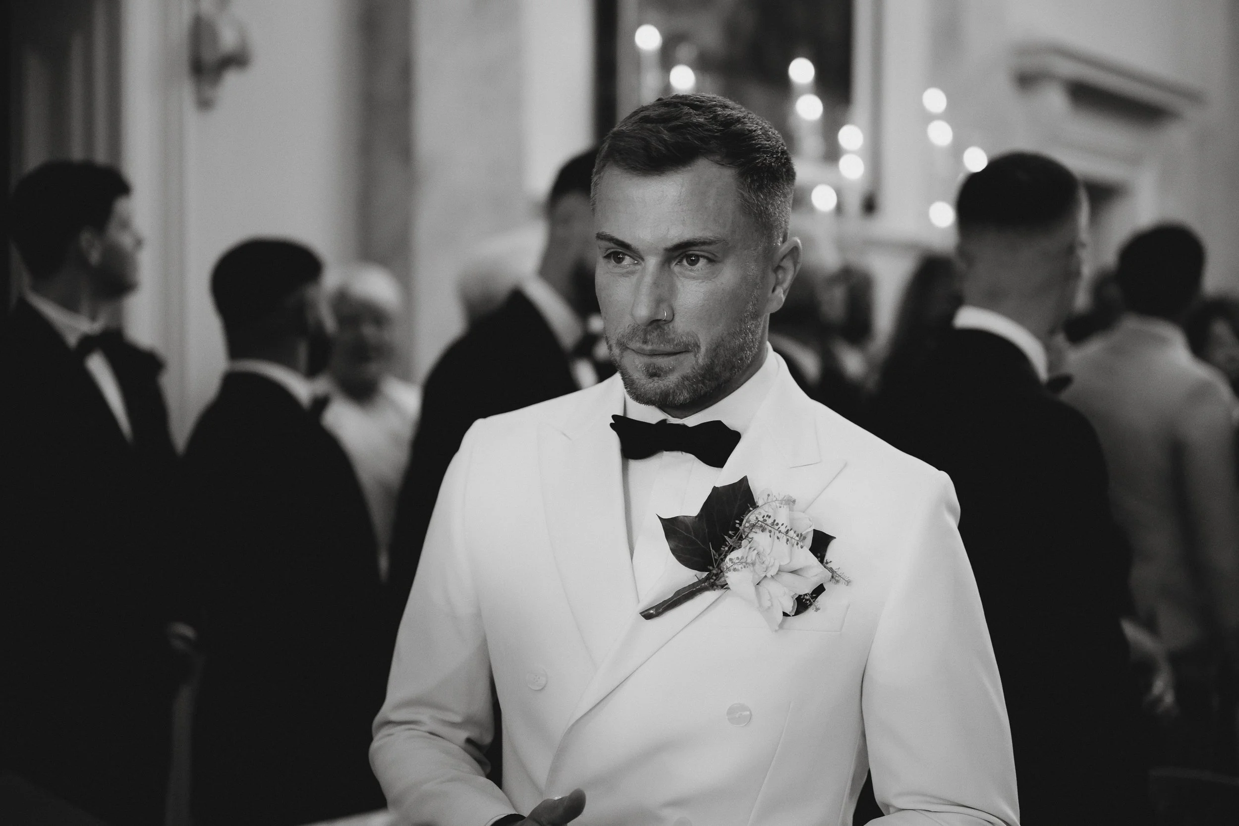Groom standing at the front of the ceremony room inside Netley Hall during his winter wedding, looking slightly nervous as he waits for his bride