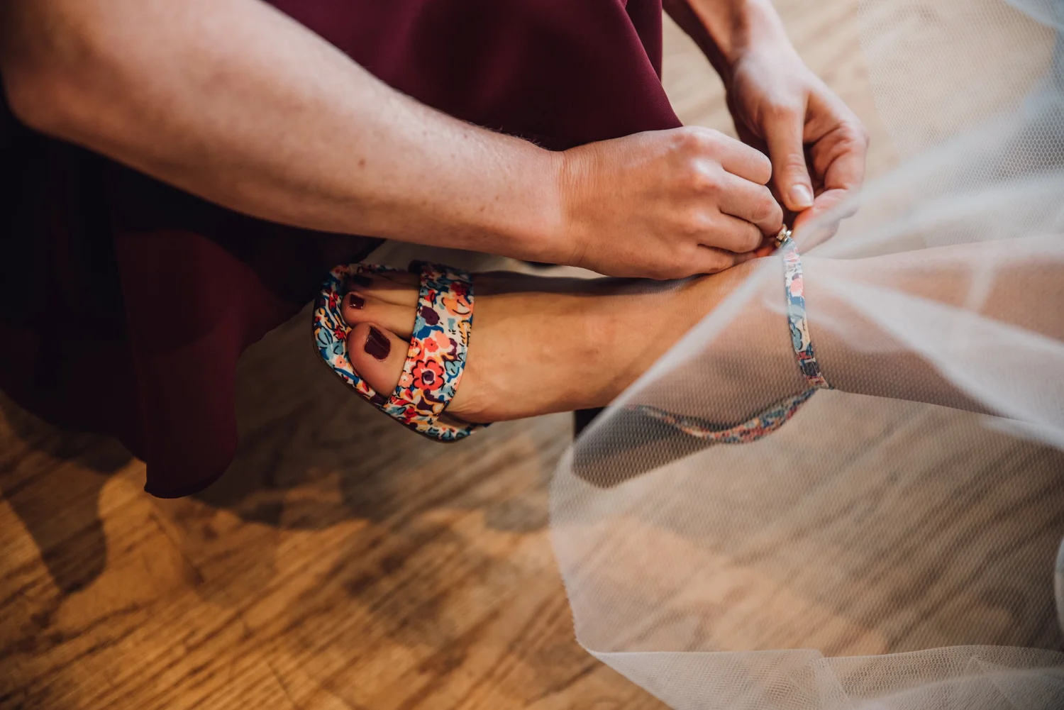 Helping a bride buckle her floral sandal