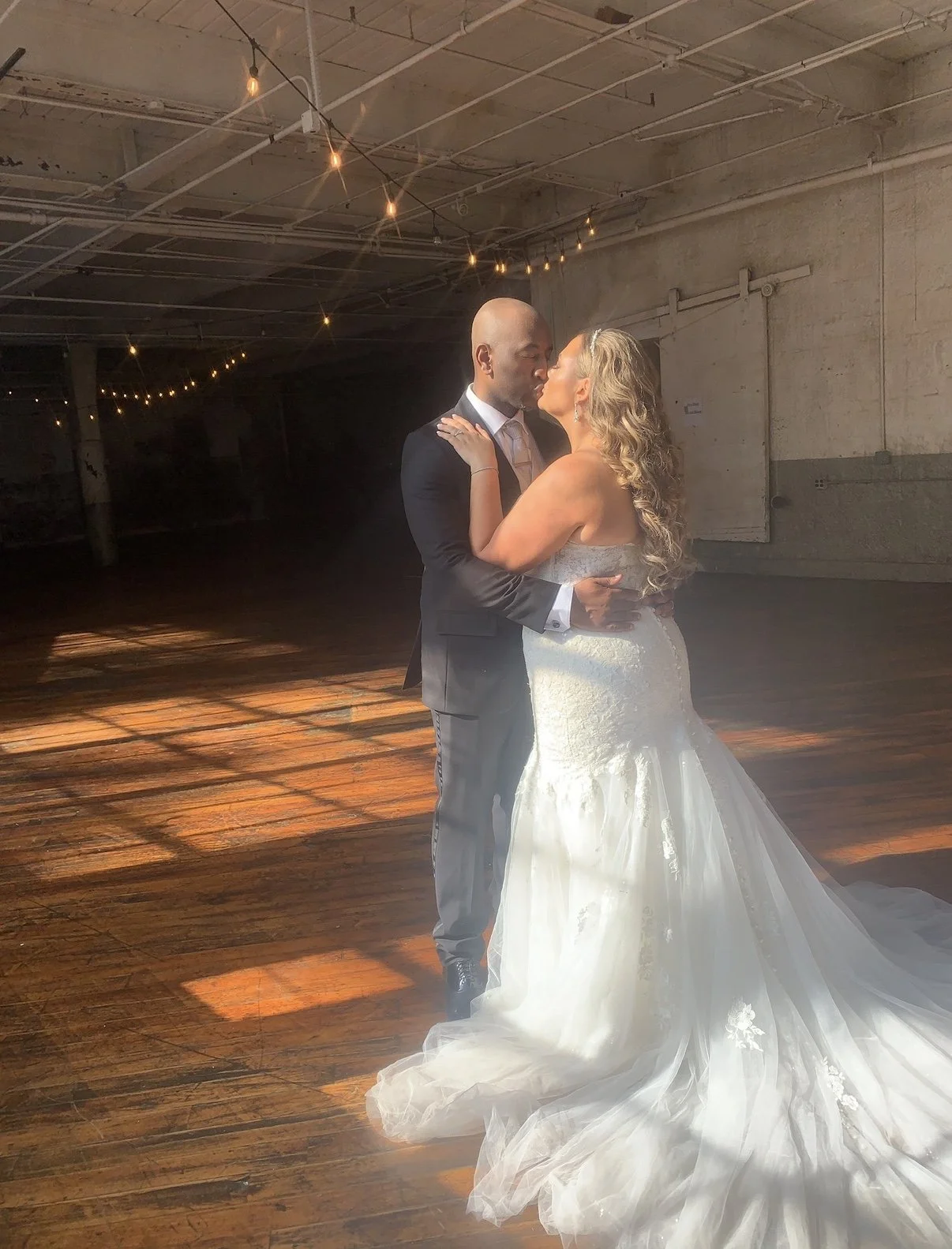 Bride and groom kissing in golden window light at a historic industrial factory wedding