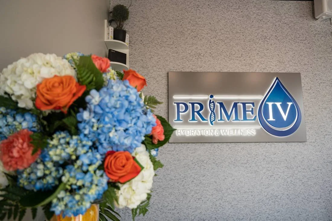 Orange roses and blue hydrangeas beside the Prime IV Hydration sign at the grand opening