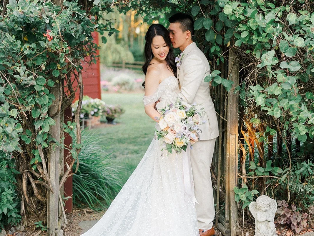 Bride and groom under a rose-covered garden arbor