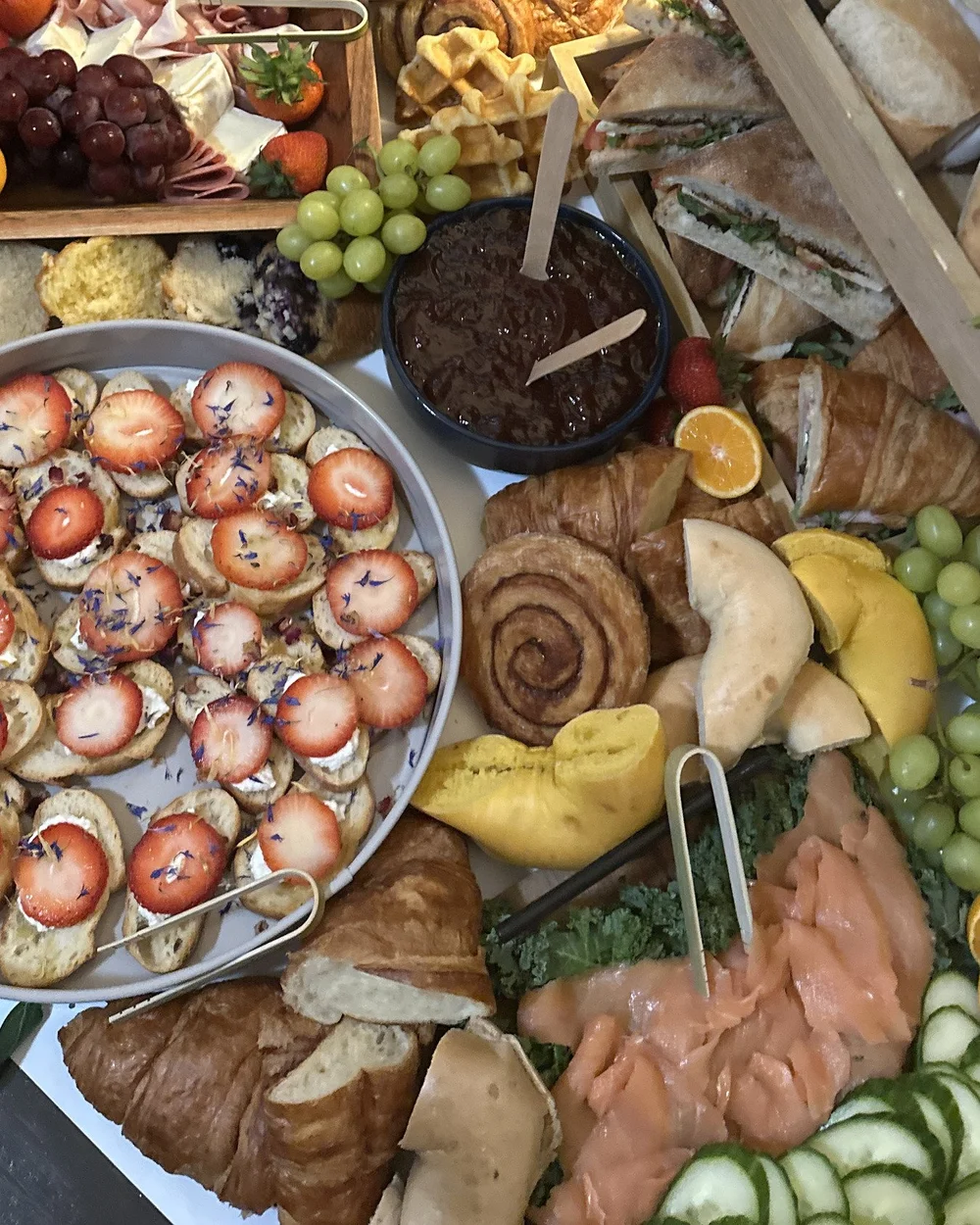 Brunch grazing table of fruit, pastries and sandwiches from above