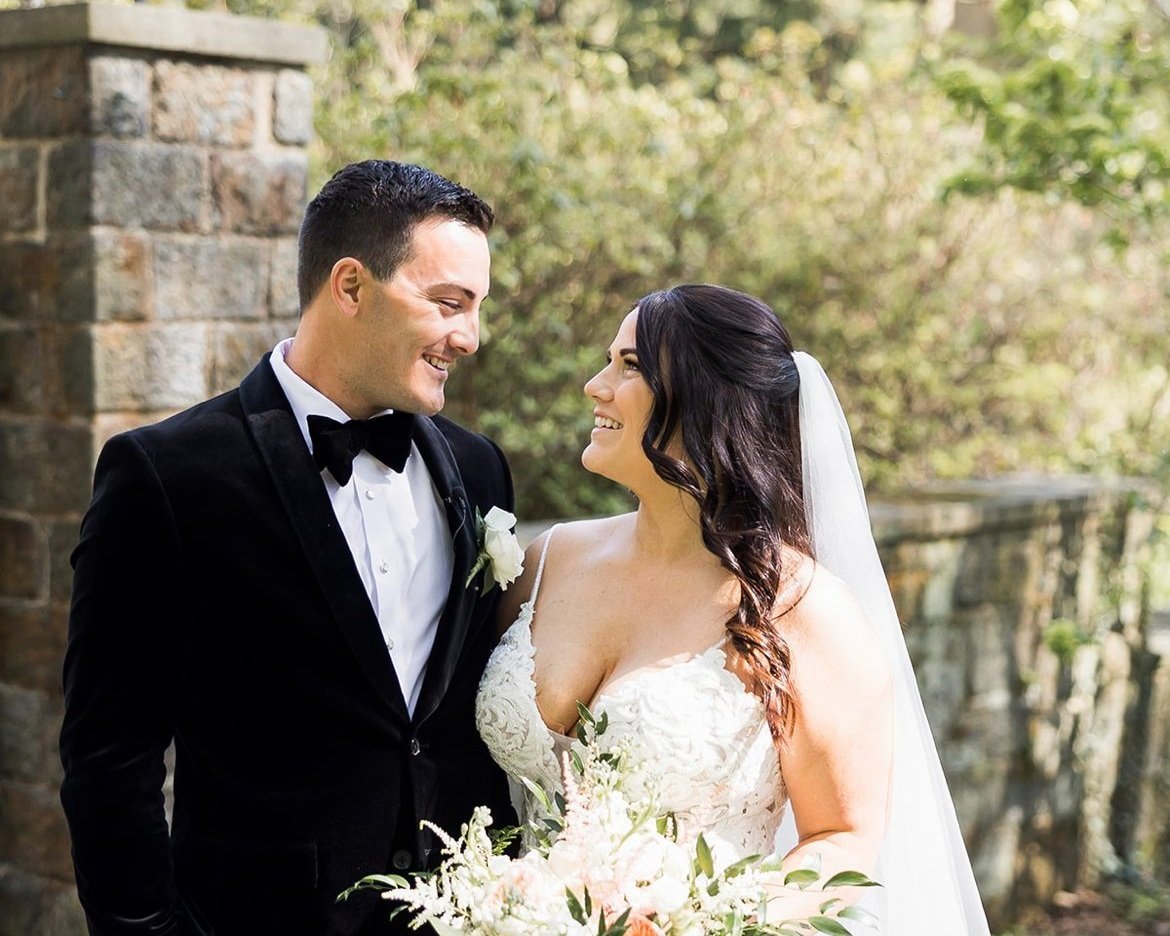 Bride and groom beside a stone gate pillar at a historic landmark wedding