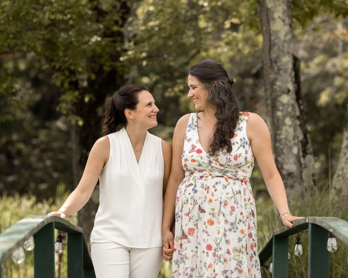 Couple holding hands on a wooded footbridge at a private estate wedding