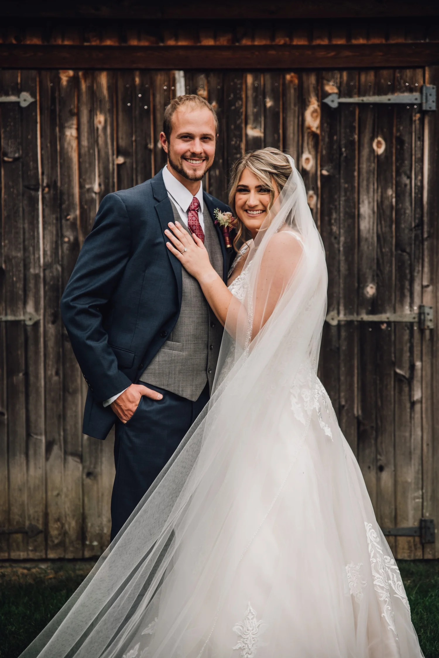 Bride and groom in front of a weathered barn door at a historic landmark wedding