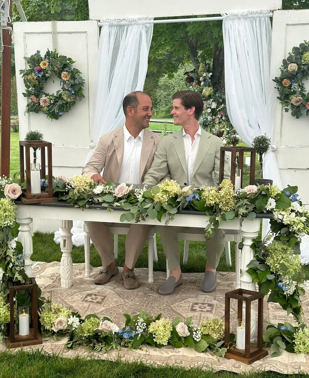 Two grooms smiling at their sweetheart table