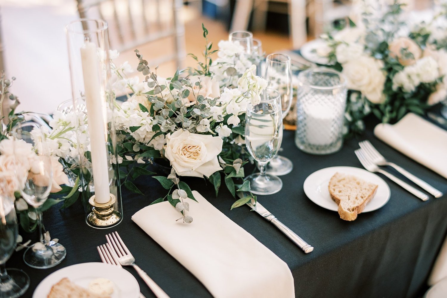 Candlelit table set with white roses and a black tablecloth