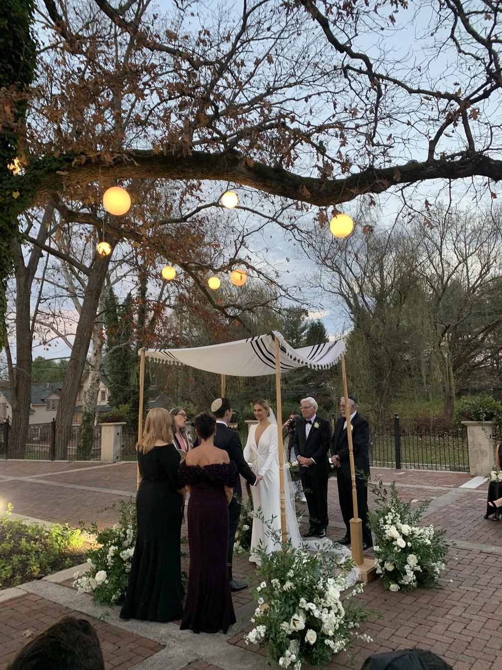 Jewish wedding ceremony under a chuppah in a brick courtyard