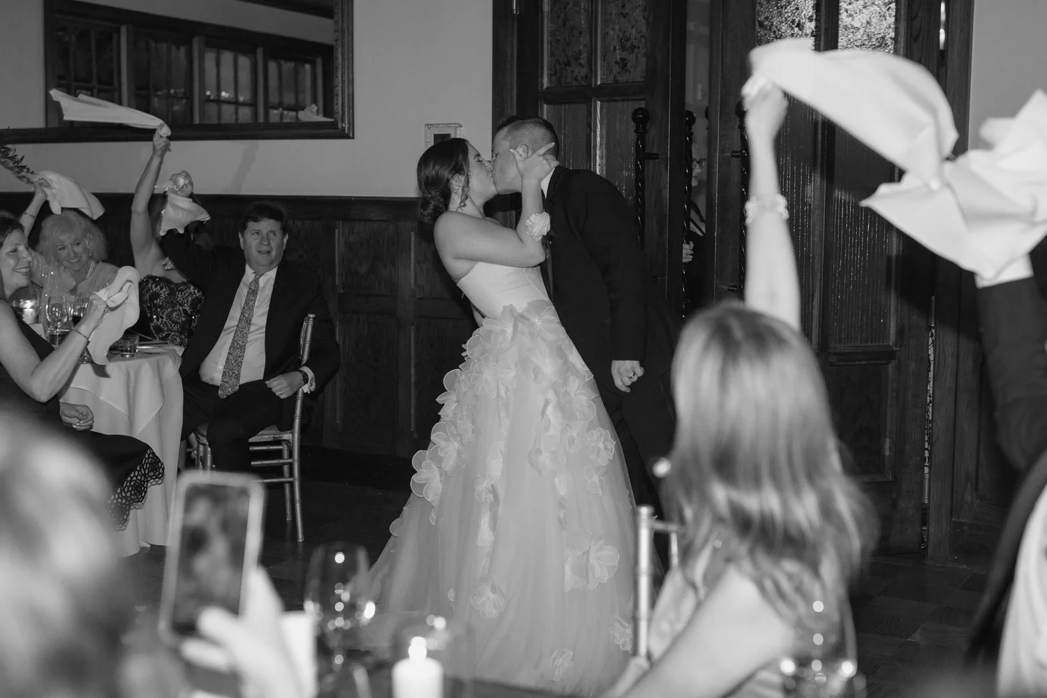 Guests waving napkins as the couple kisses at a historic landmark wedding reception
