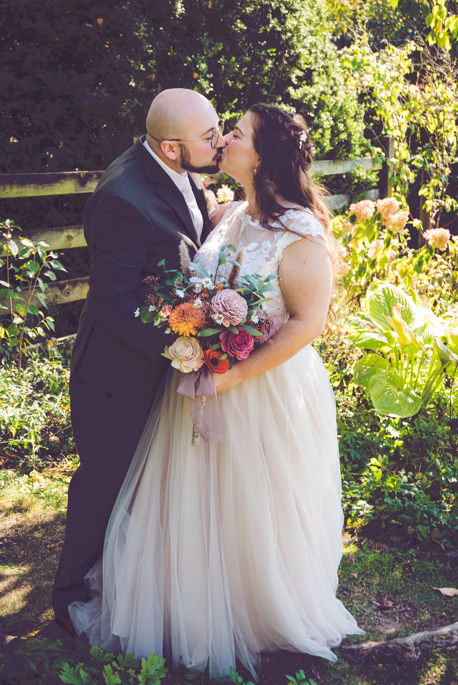 Bride and groom kissing in a sunlit garden at a farm and garden wedding