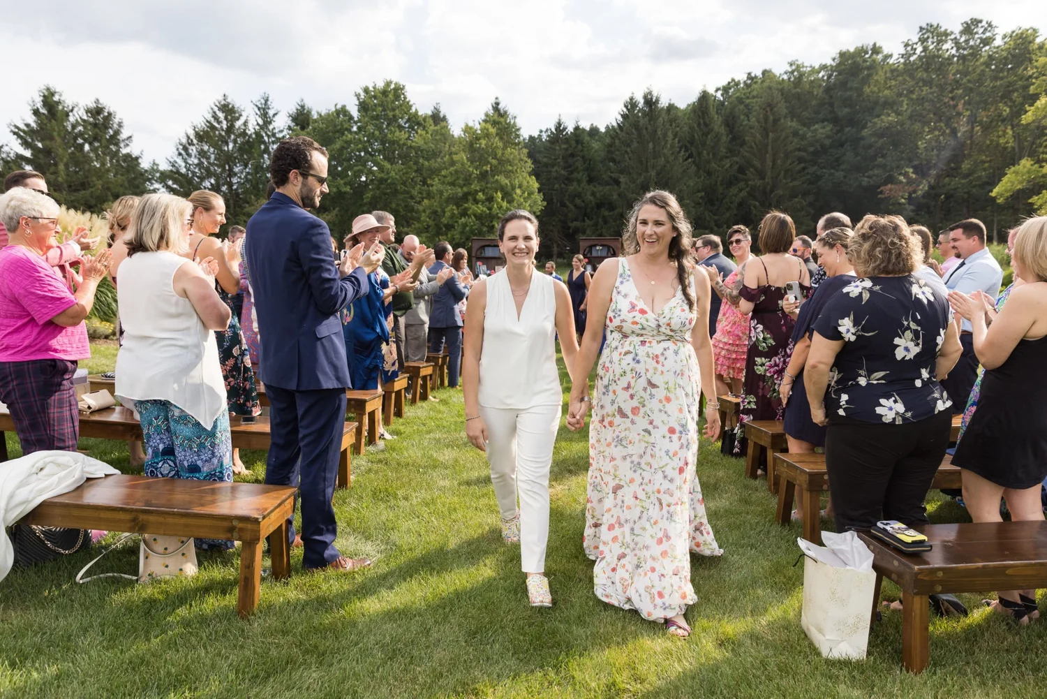 Couple walking back up the aisle past cheering guests on a lawn