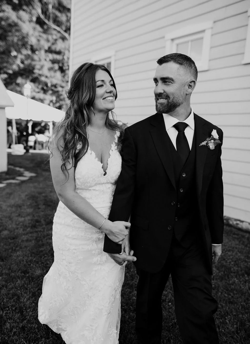 Black and white portrait of a bride and groom beside a white barn at a private estate wedding