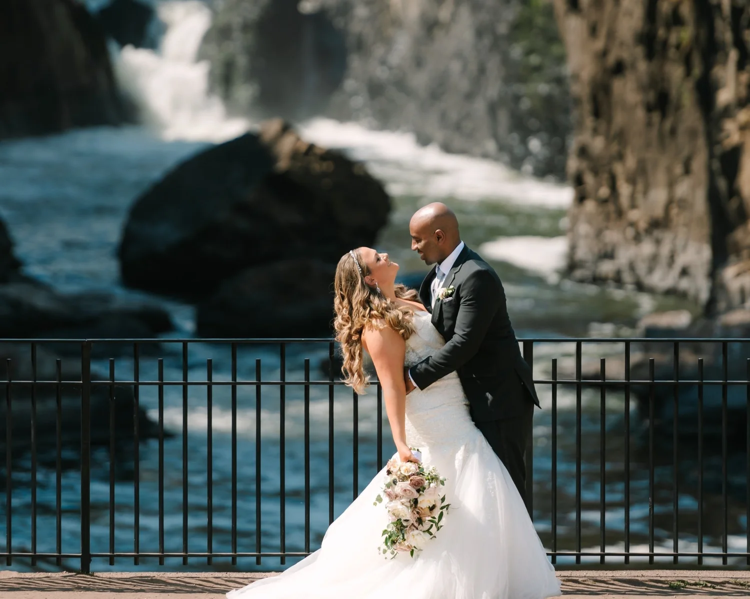 Bride and groom kissing at a railing by the water
