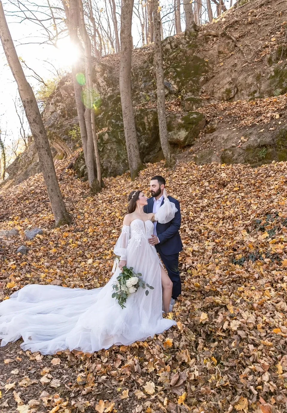 Bride and groom in autumn leaves on a wooded hillside at a historic landmark wedding