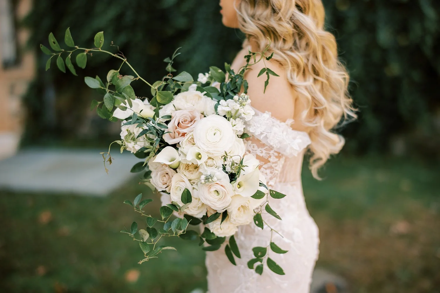 Bride holding a white rose and greenery bouquet