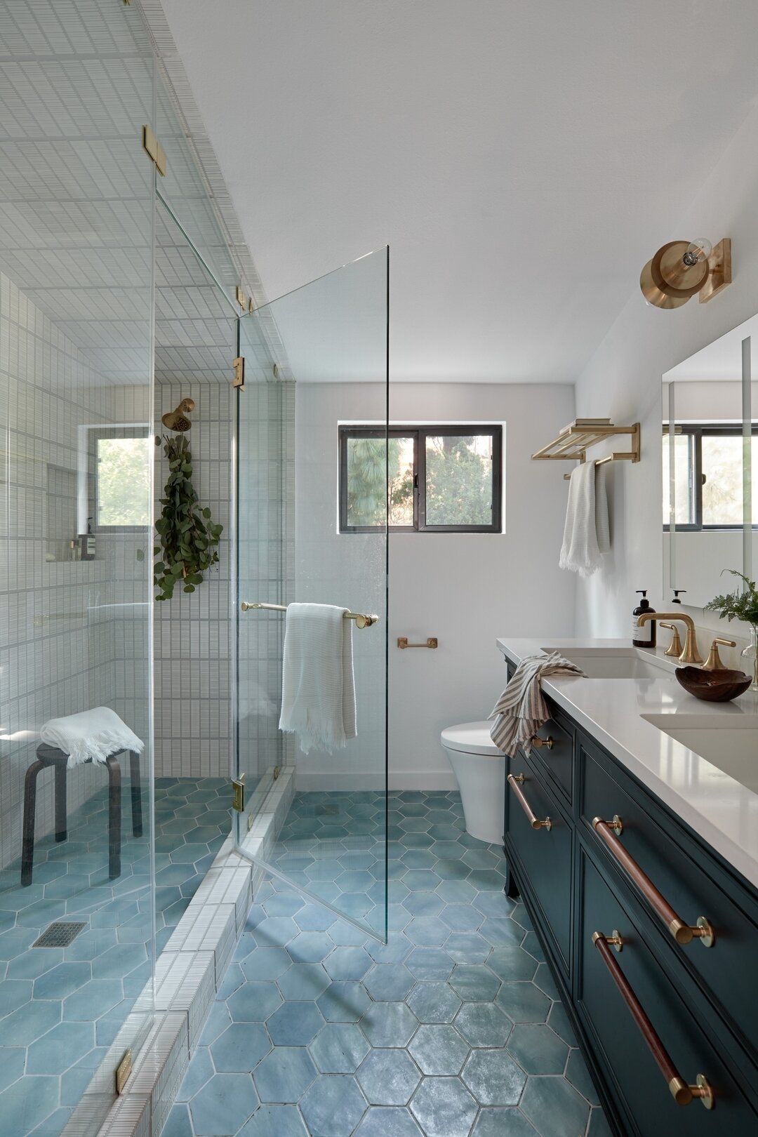 Our #Treehouse guest bathroom transformation is one for the books. We were able to make the space larger while also updating the vanity, entire shower, and fixtures. The combination of blues and brass is to die for. Swipe to see the &quot;before&quot