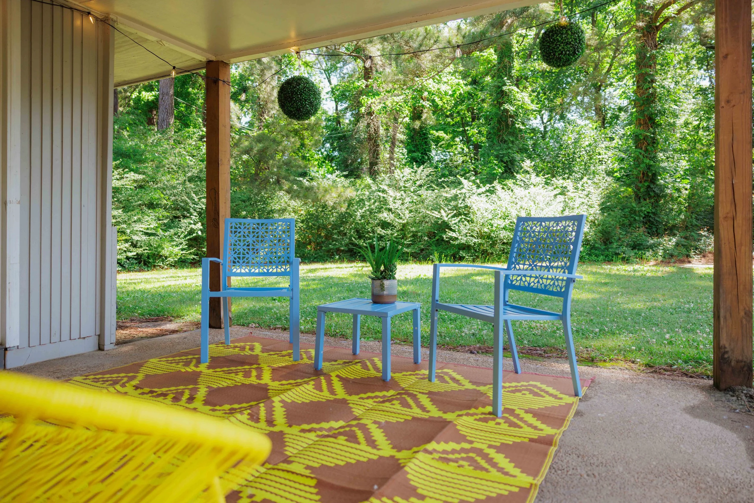 A covered outdoor patio surrounded by mature greenery and quiet backyard views.