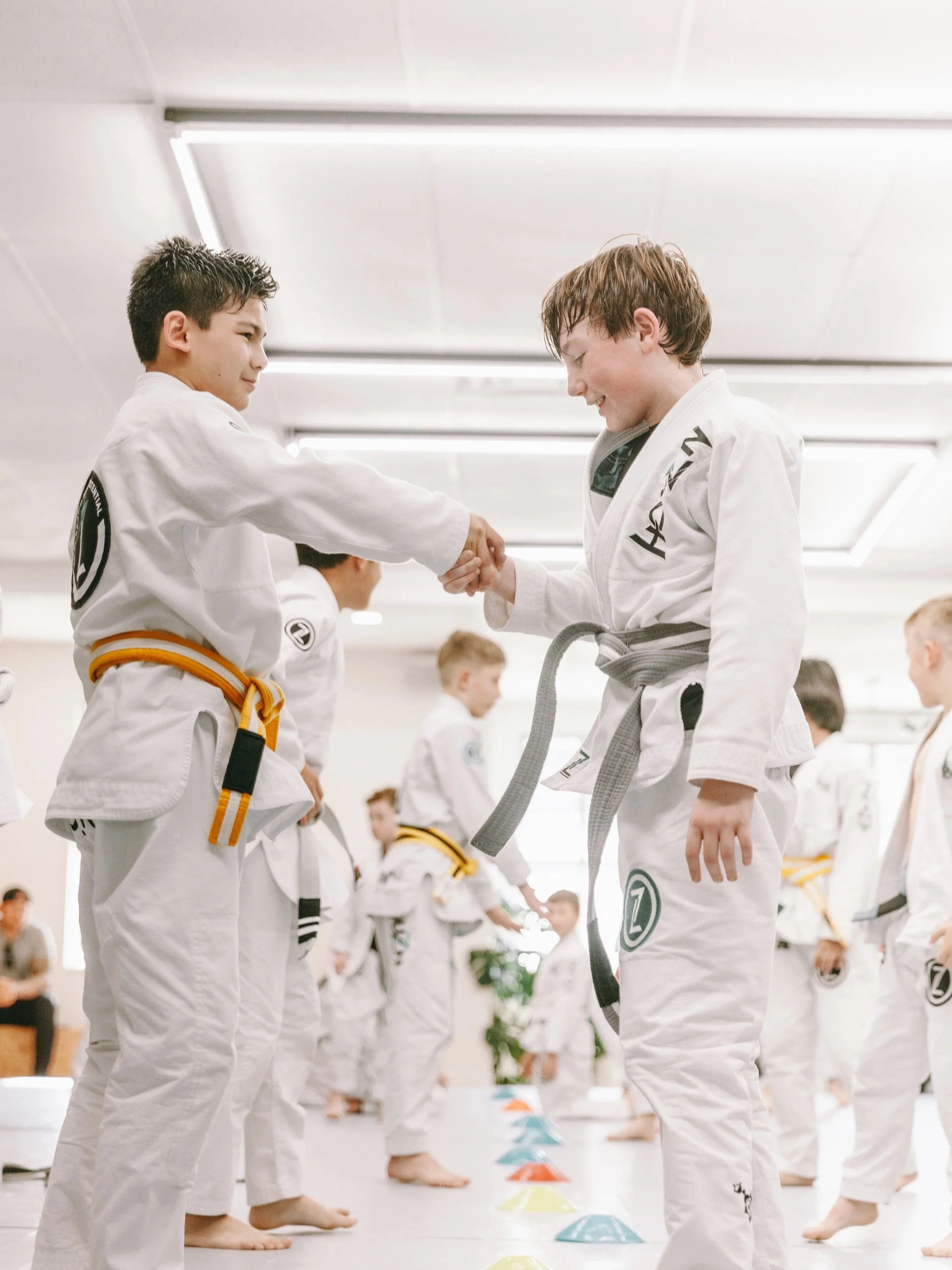 Two kids in gi shake hands during kids Brazilian Jiu Jitsu class at Houzn Jiu Jitsu Academy in Mount Pleasant, SC.