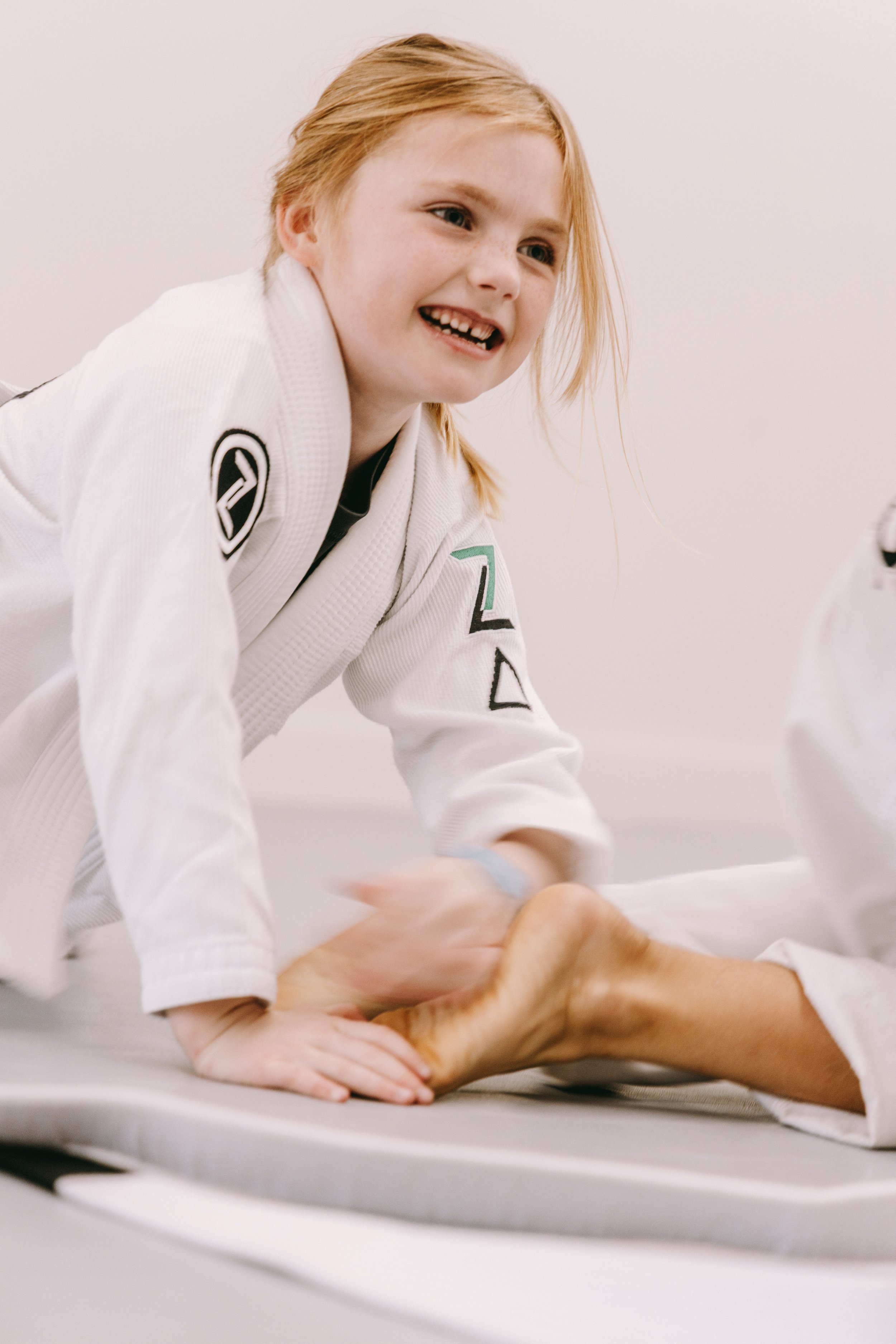 Close-up of a young student in a white gi during kids jiu jitsu training on the mat.