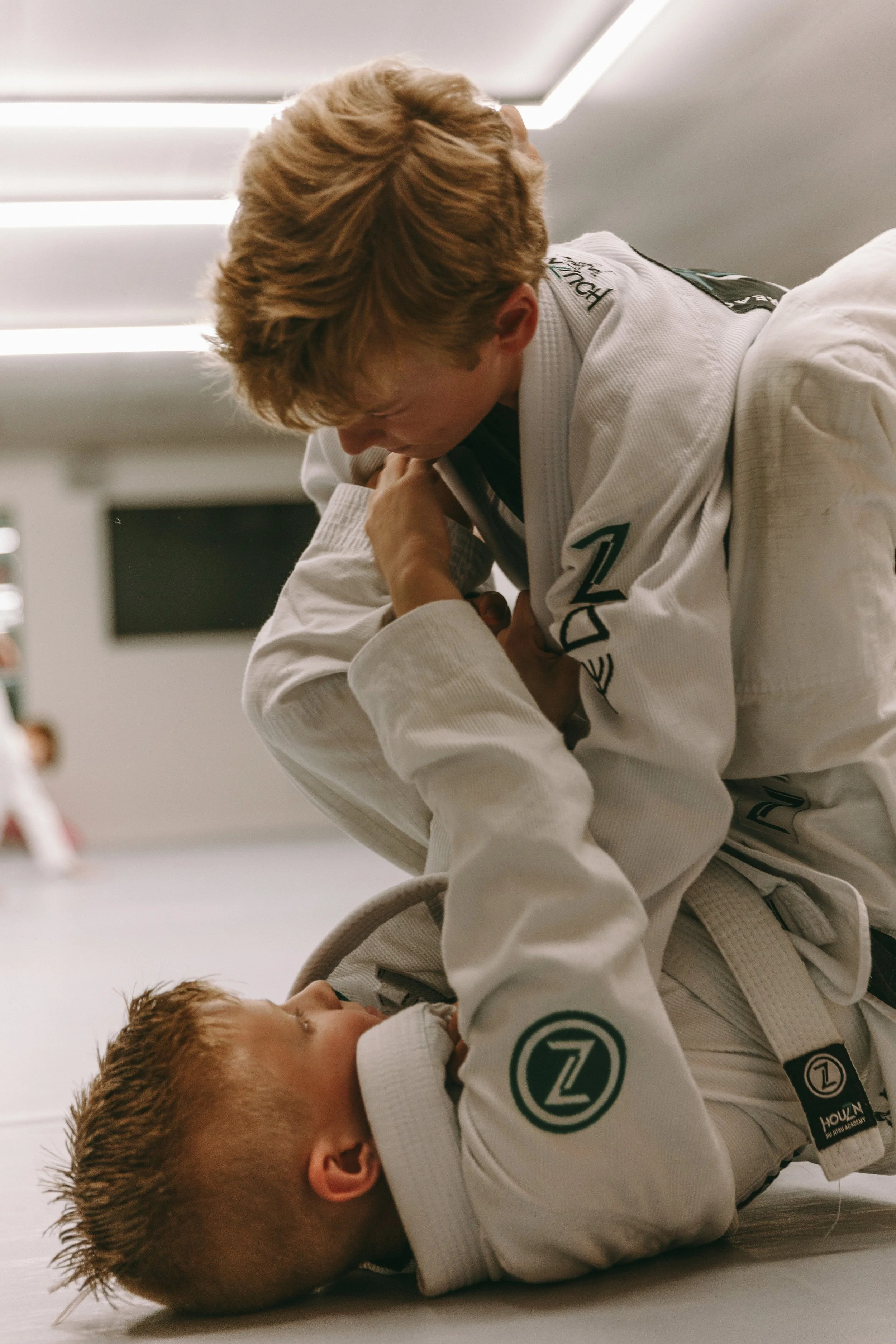 Kids Brazilian jiu jitsu partners training from guard position at Houzn Jiu Jitsu Academy.