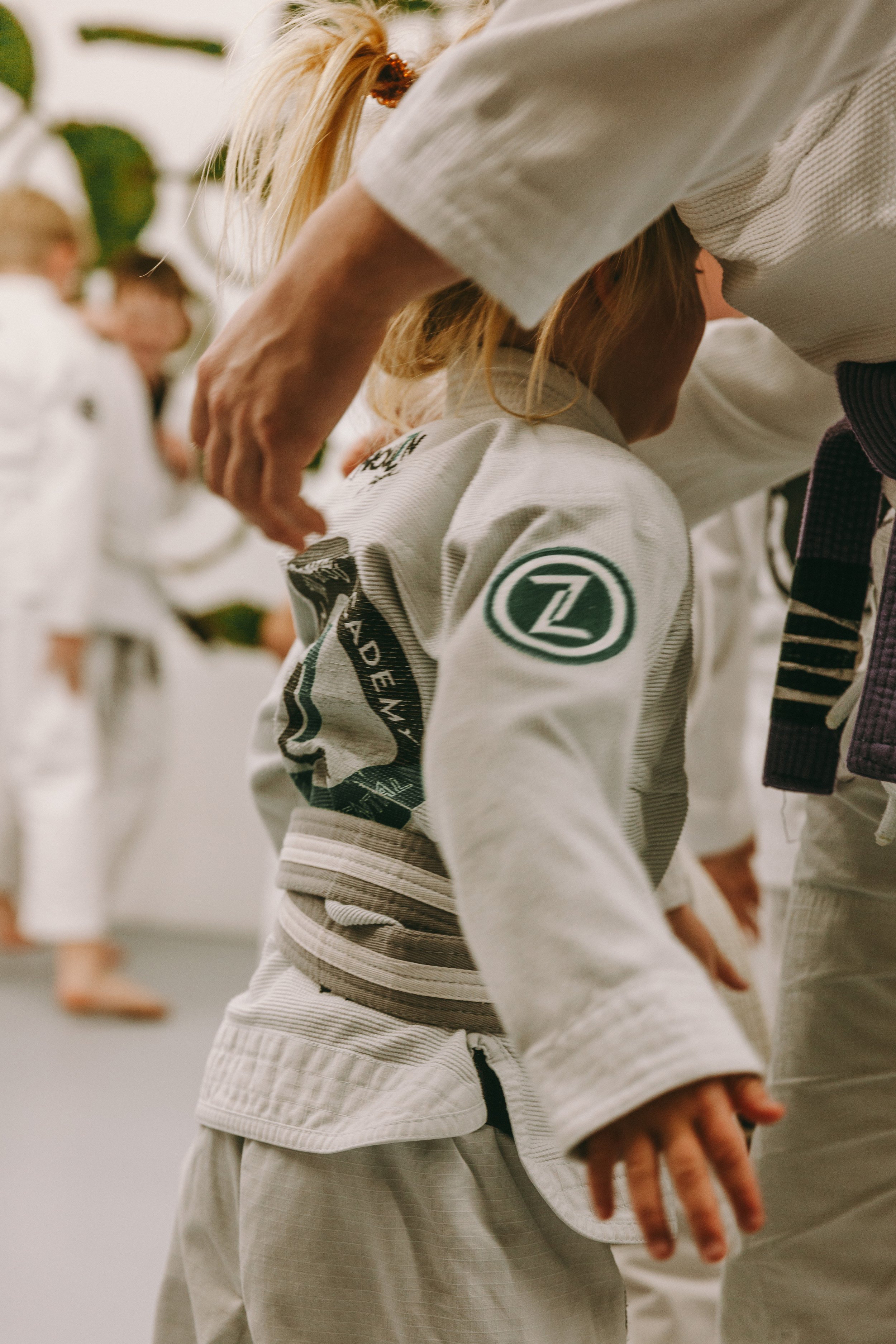 Coach helping a child adjust their gi at Houzn Jiu Jitsu Academy during kids Brazilian jiu jitsu class