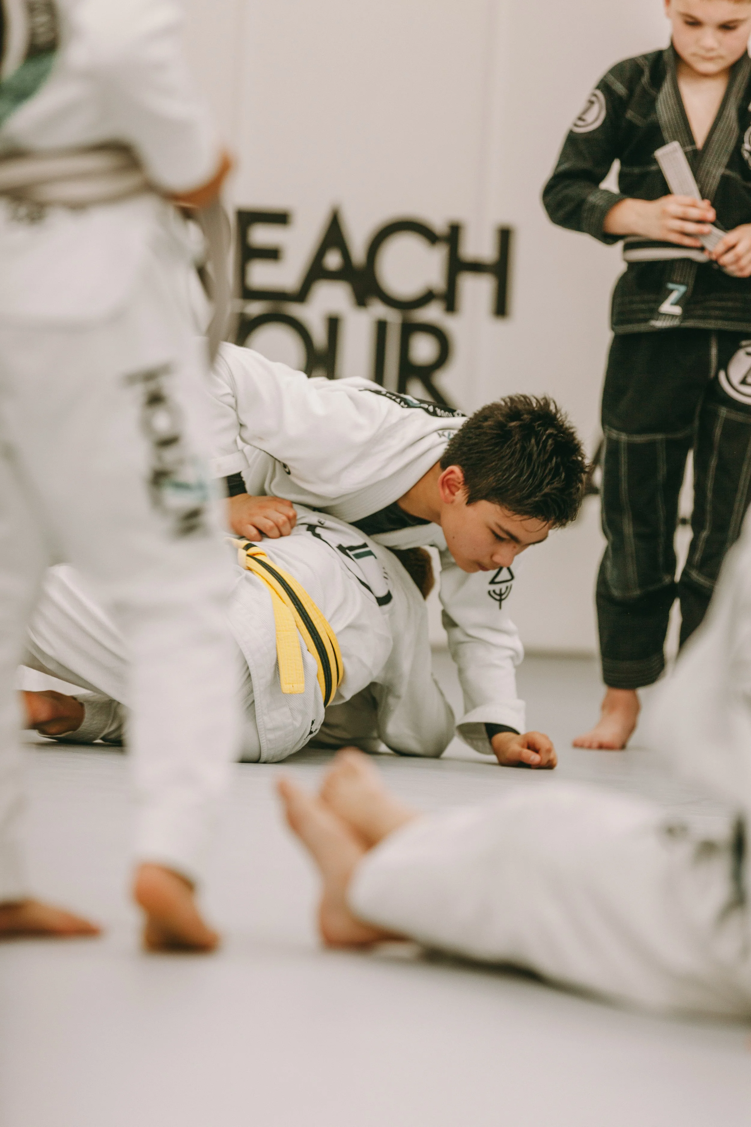 Kids Brazilian Jiu Jitsu belt promotion moment at Houzn Jiu Jitsu in Mount Pleasant, SC, with coaches and students watching respectfully.