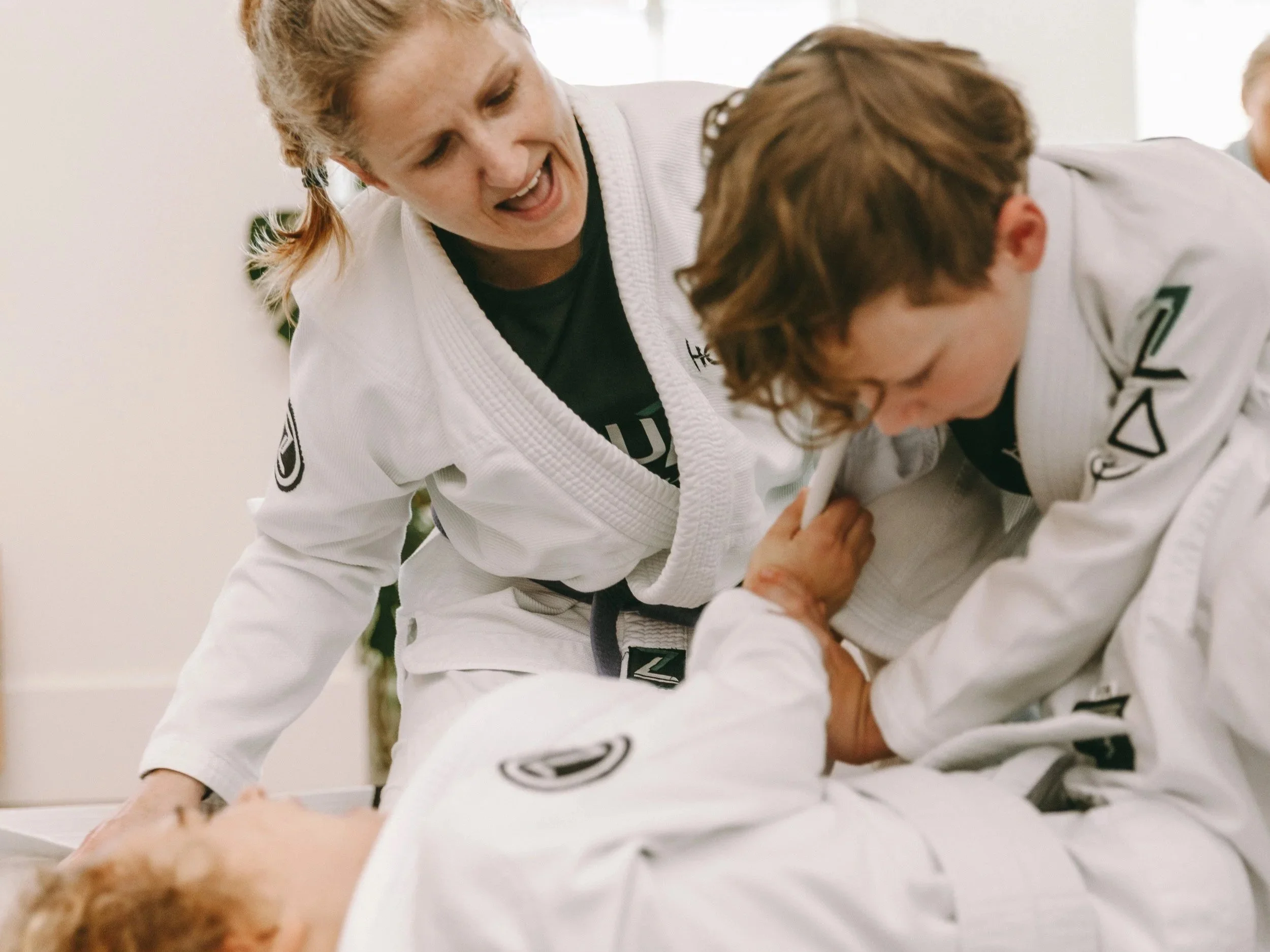 Kids BJJ coach giving hands-on instruction during Brazilian Jiu Jitsu class at Houzn Jiu Jitsu Academy in Mount Pleasant, SC.