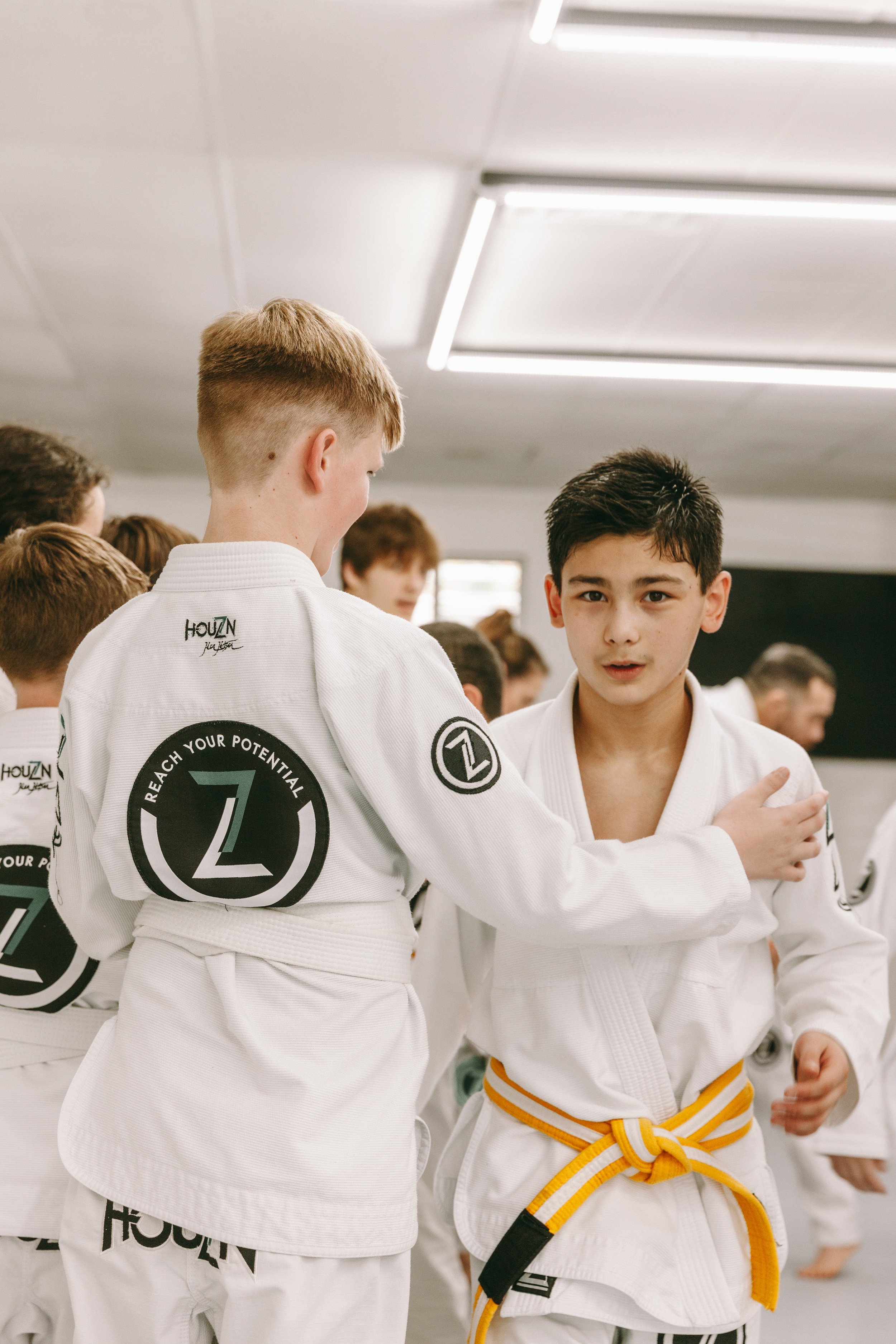 Kids at end practice partner greeting in white gis at Houzn Jiu Jitsu Academy in Mount Pleasant, SC.
