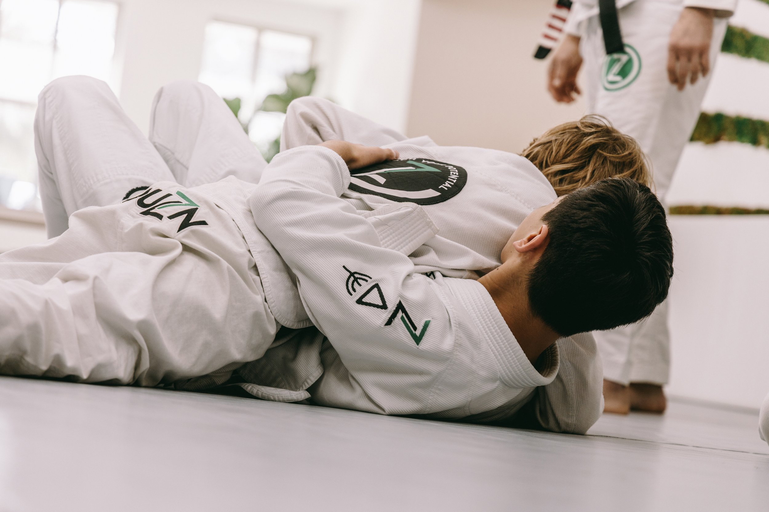 Two kids practice a ground control position during Brazilian jiu-jitsu class at Houzn Jiu Jitsu Academy in Mount Pleasant, SC.