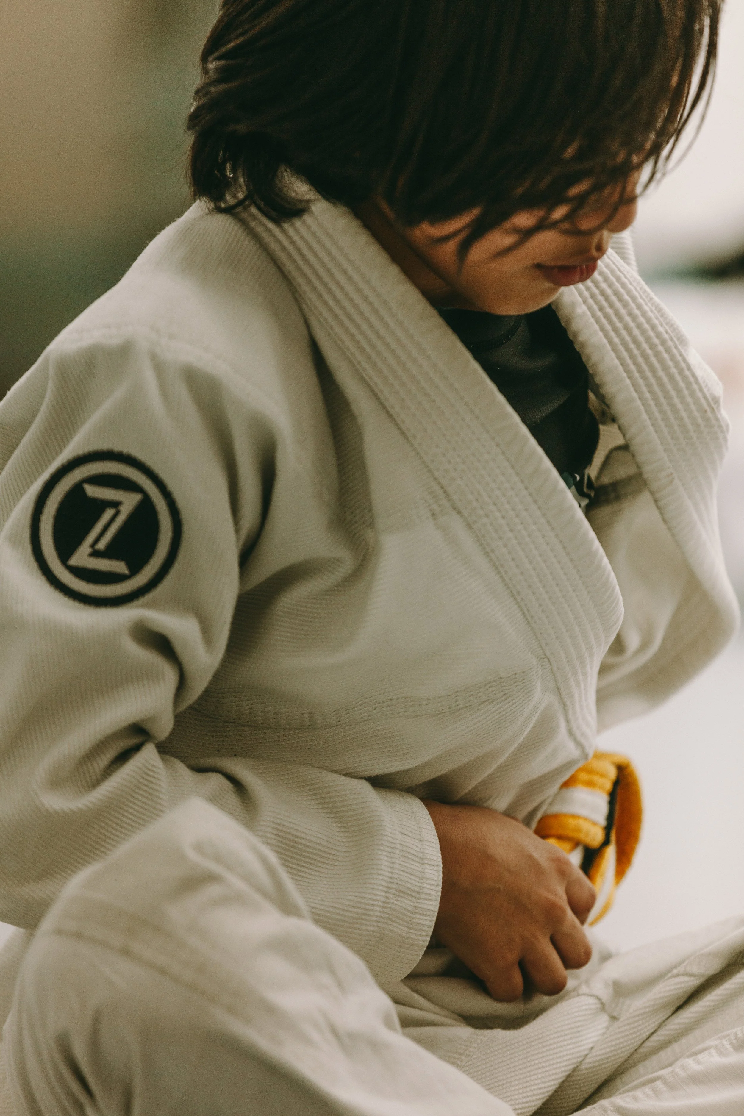 Kids Brazilian jiu jitsu student at Houzn Jiu Jitsu Academy adjusting a gi with a yellow belt during class